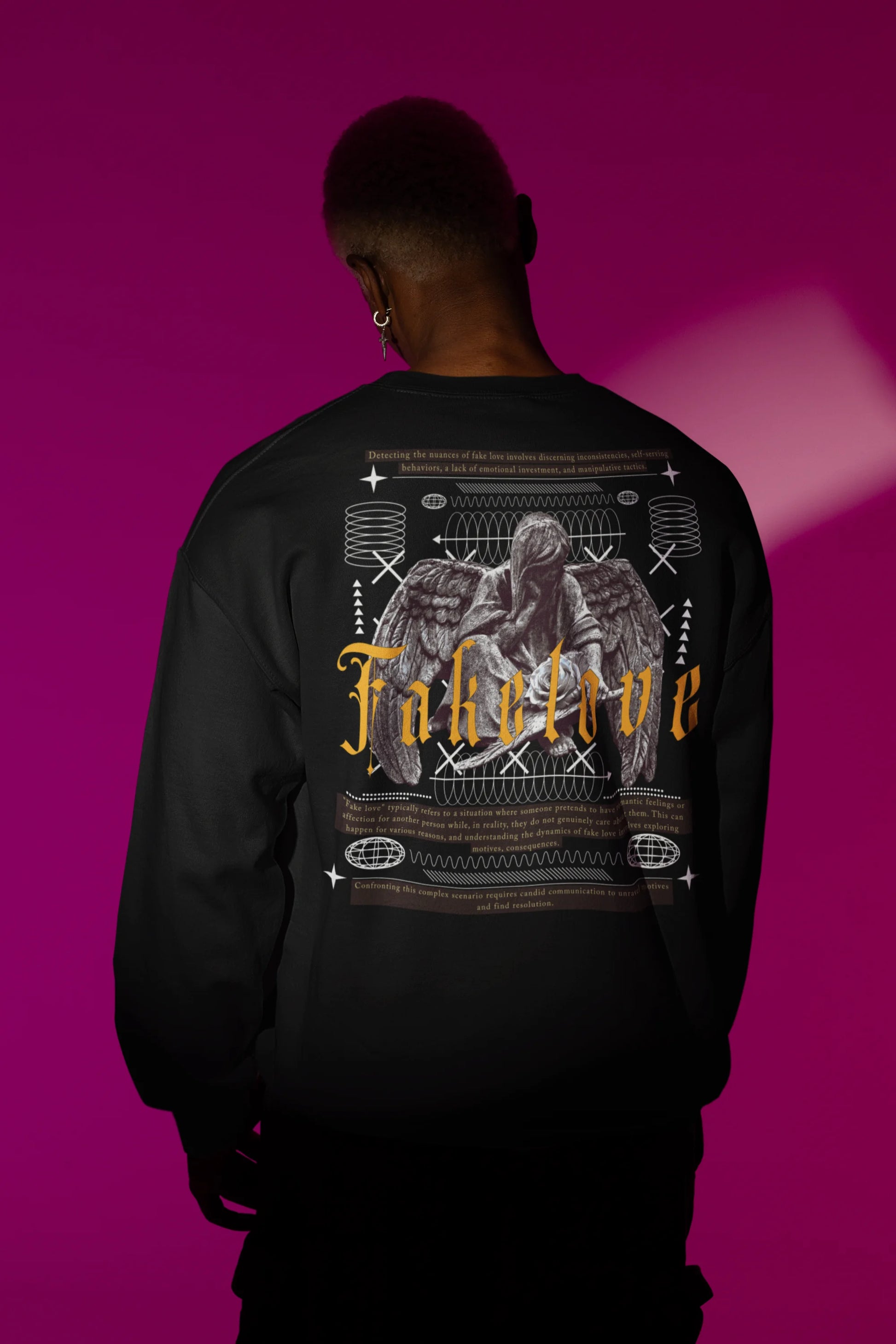 First back view of a male model wearing a black sweatshirt with a brutalist design featuring a fallen angel statue and the phrase "Fake Love".