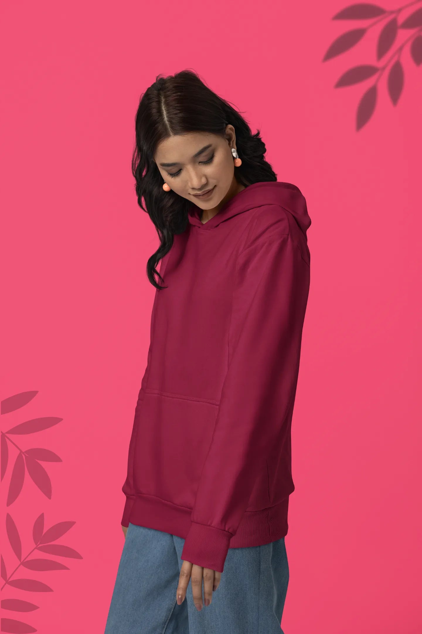 Second front view of a female model wearing a maroon hoodie with a design of a wildcat sitting on ocean waves.