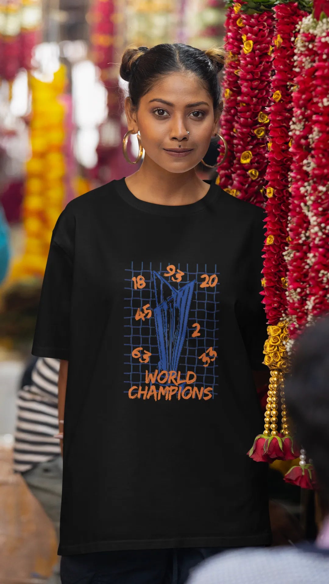 Third front image of female model wearing a black oversized t-shirt featuring the World Cup 2024 trophy with the text "World Champions" underneath. Ideal for Indian cricket fans celebrating their team's victory.