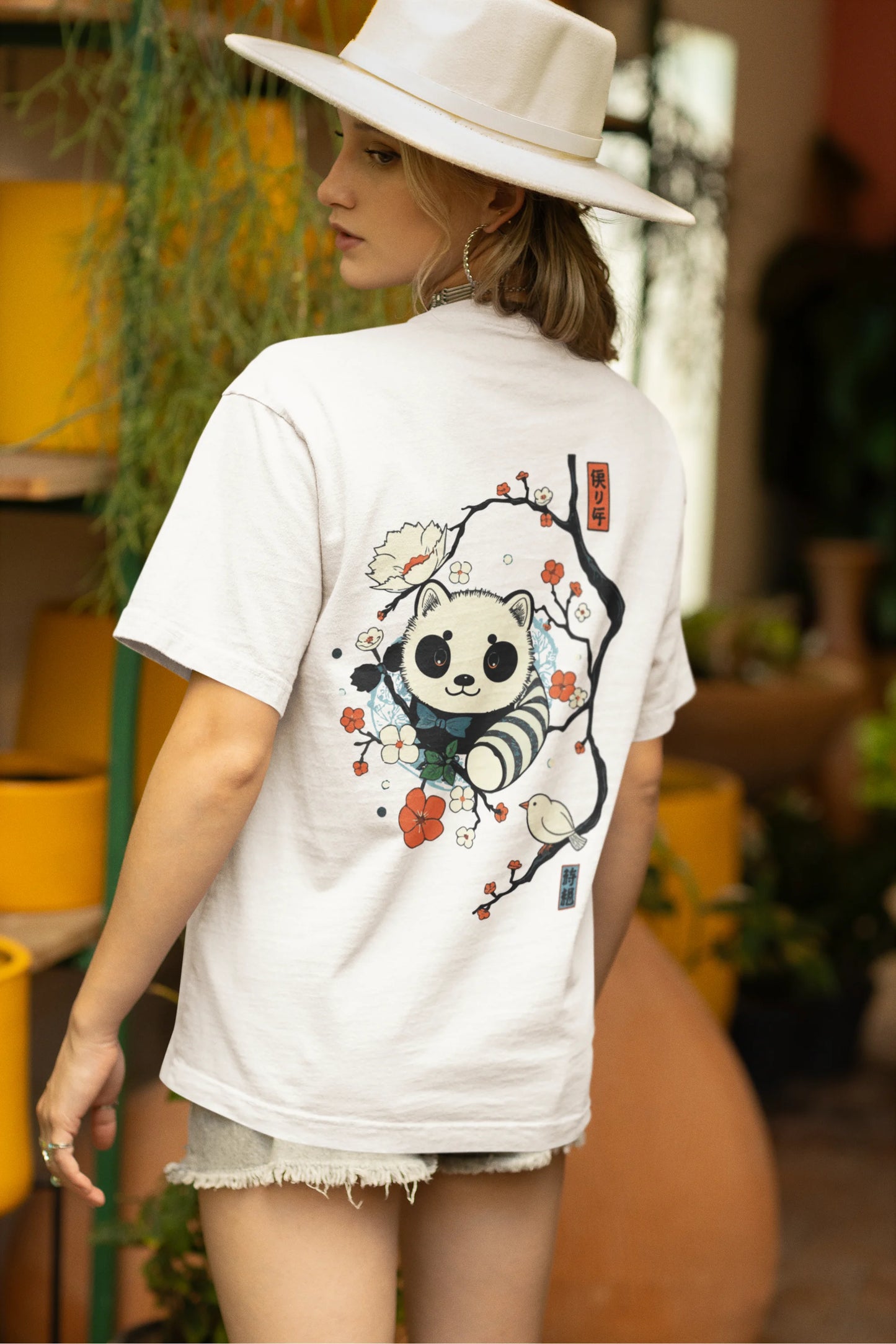 Back view of a female model wearing a off white oversized tee with a panda fox surrounded by bamboo.