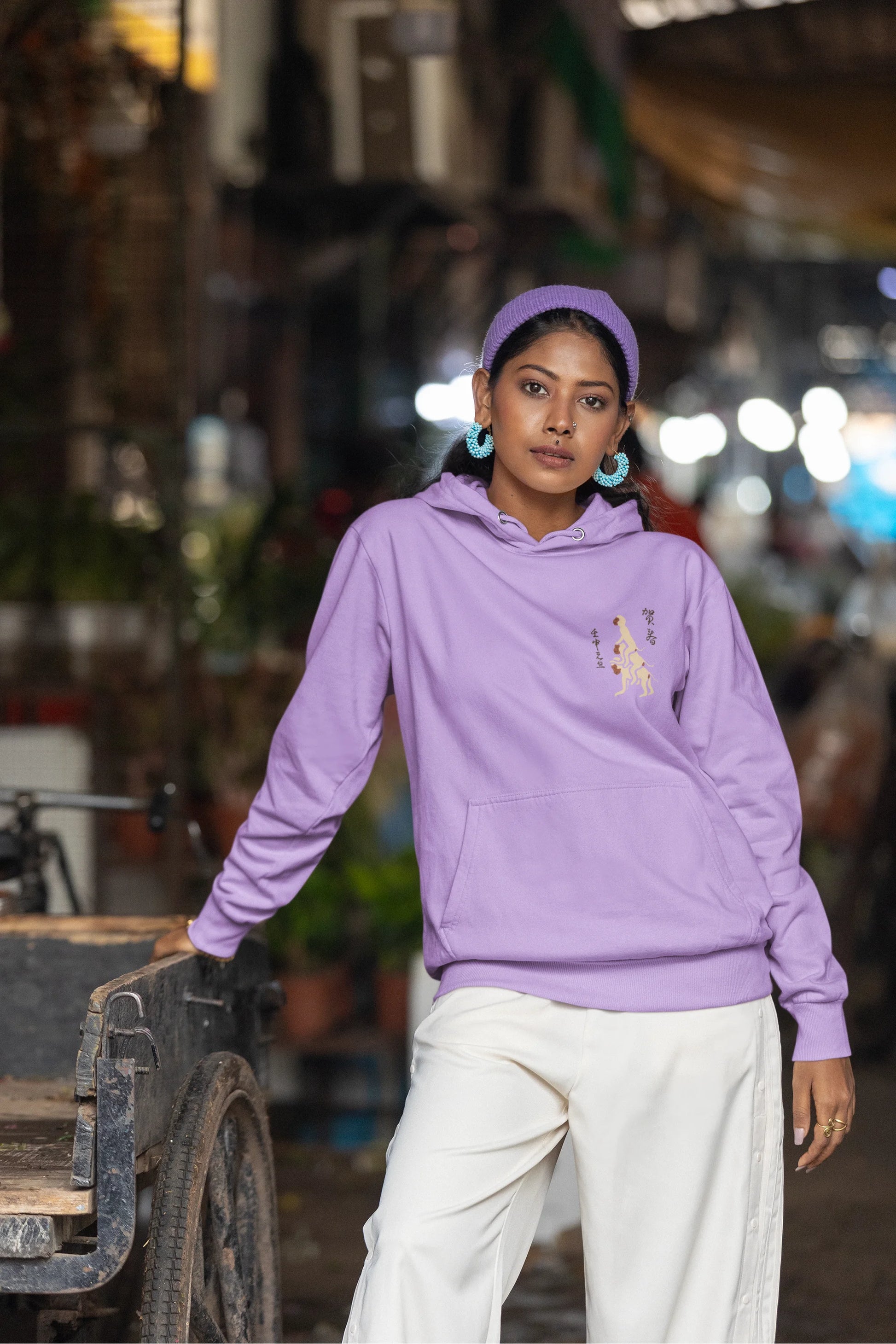 Third front view of a female model wearing a lavender hoodie with a design of the three wise monkeys: "See no evil, hear no evil, speak no evil."