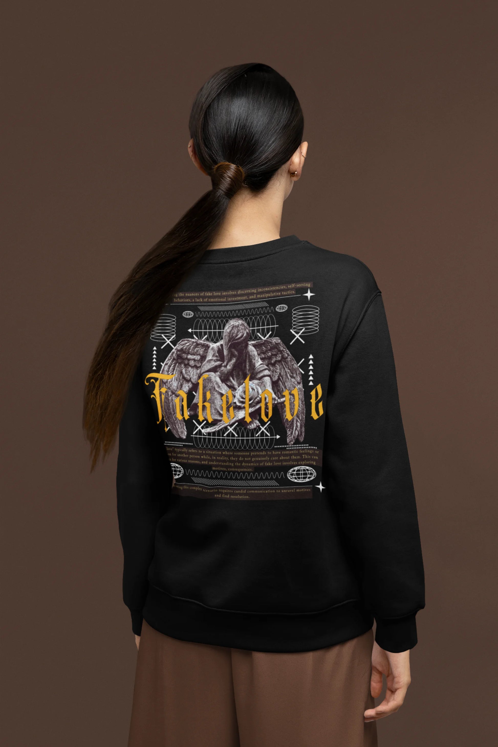 Back view of a female model wearing a black sweatshirt with a brutalist design featuring a fallen angel statue and the phrase "Fake Love".