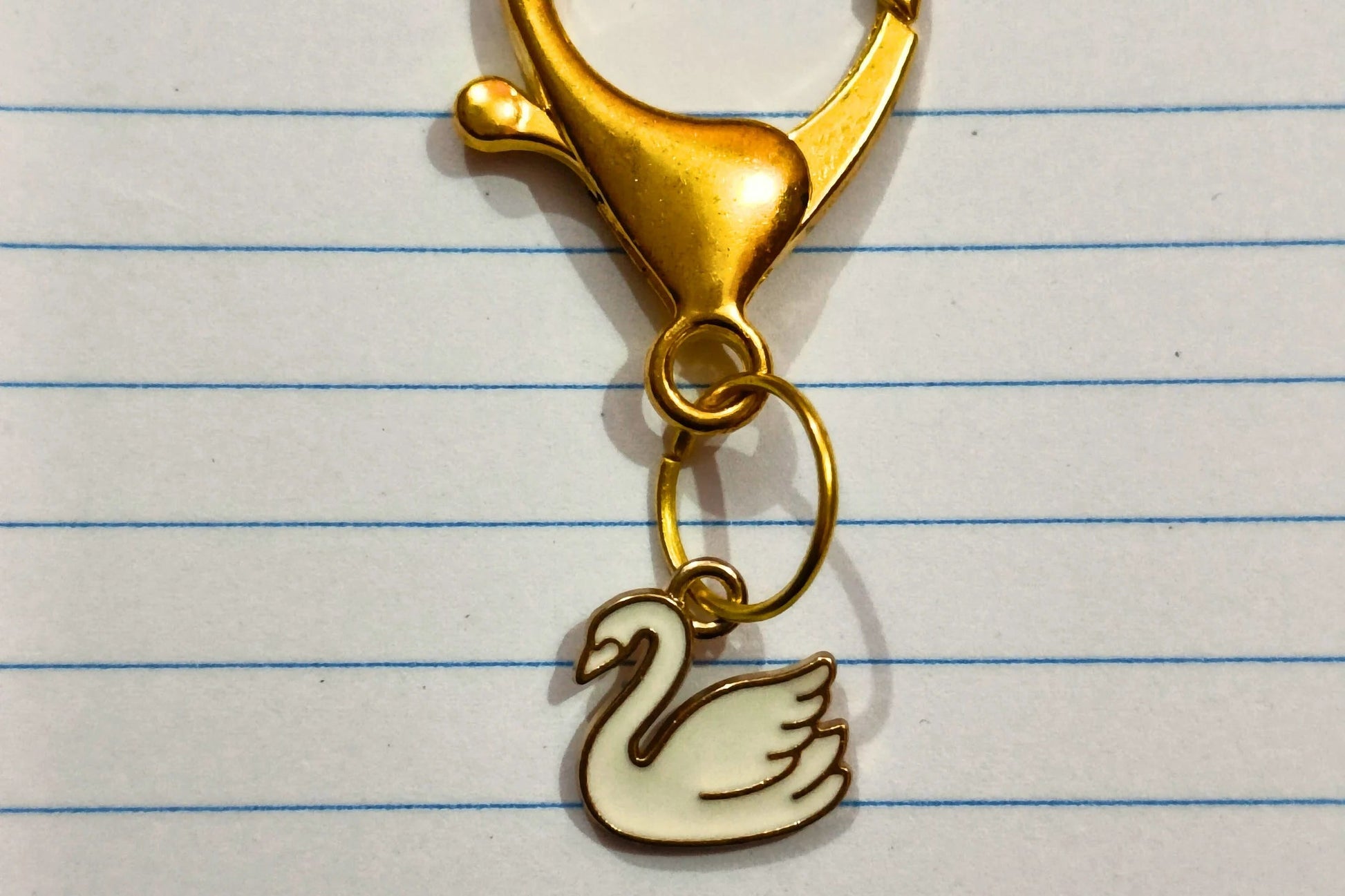 A couples keychain featuring two separate charms: one of a white swan.