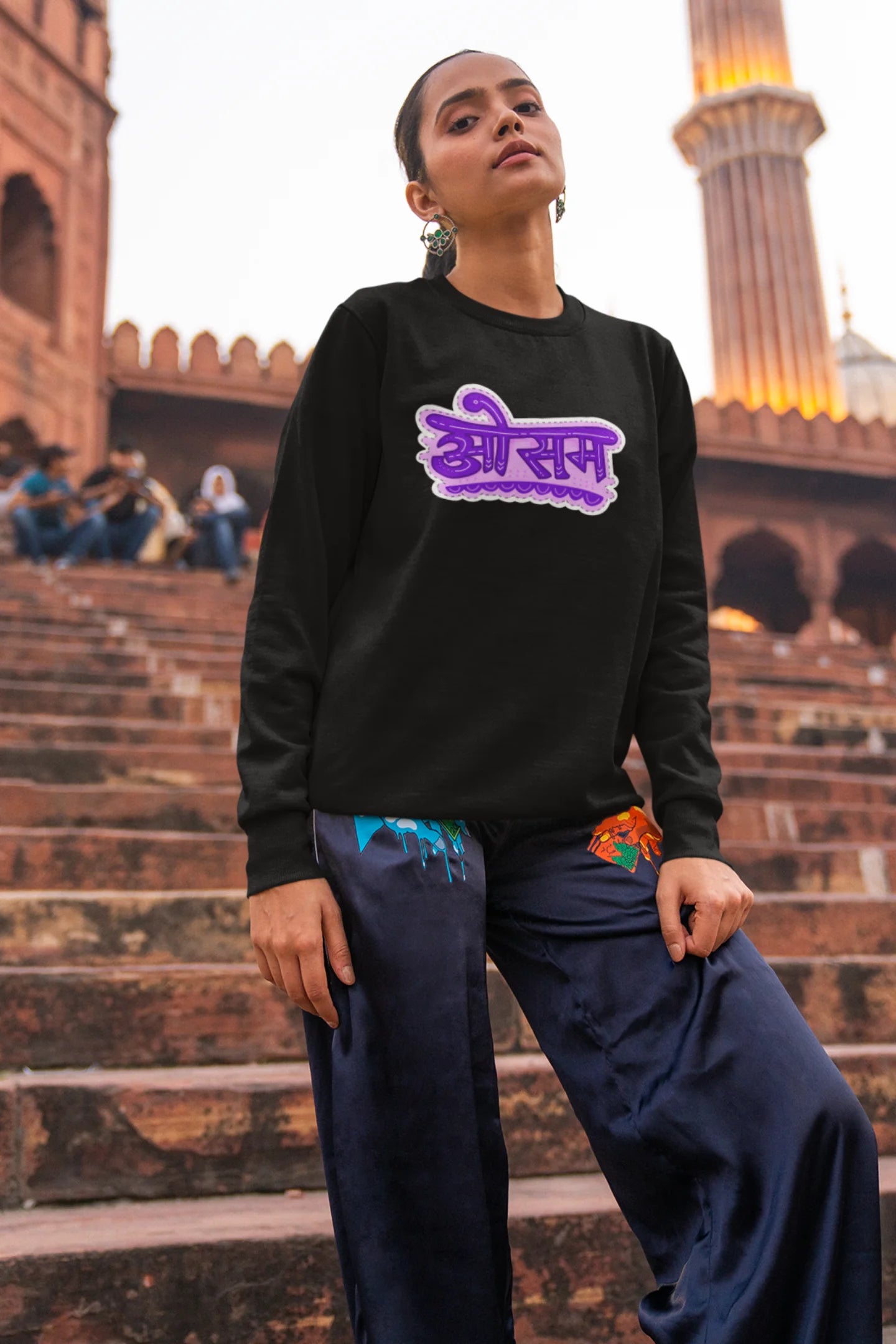 4th front view of a female model wearing a black colored oversized graphic t-shirt featuring the word "awesome" in a Hindi script.