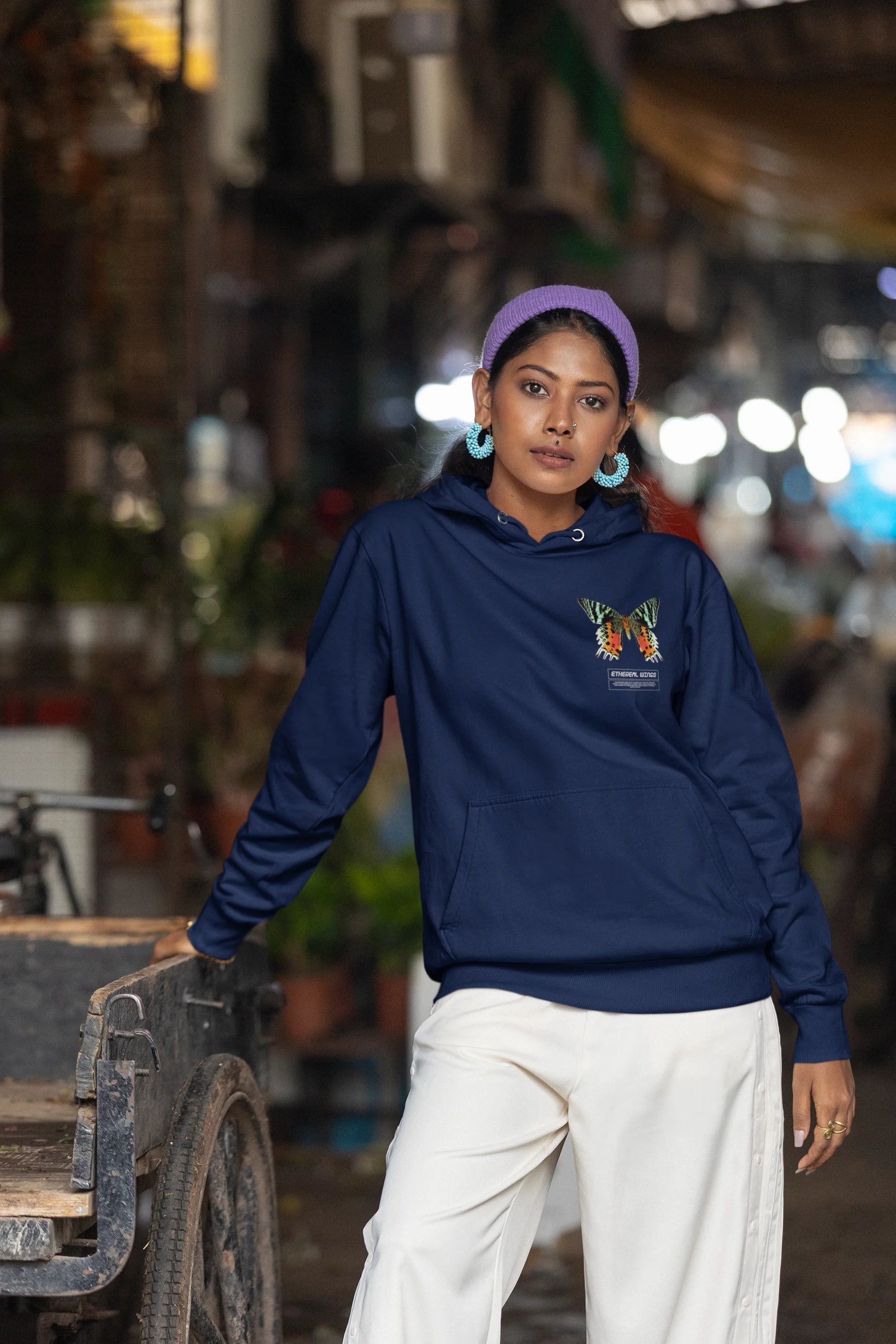 Fifth front view of a female model wearing a navy blue hoodie with a glowing butterfly design, symbolizing the ethereal beauty of nature.