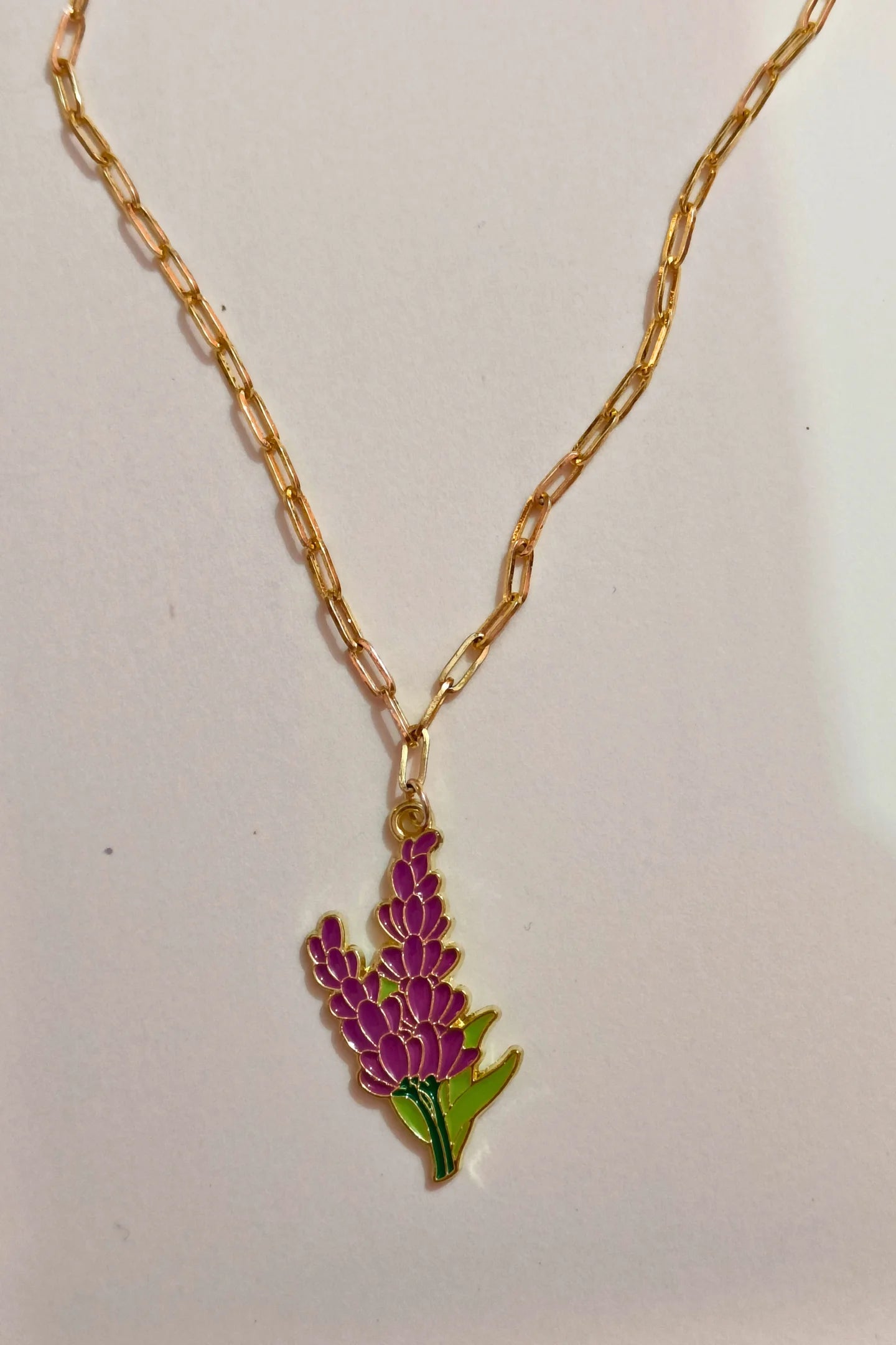 2nd view of a gold chain necklace with a small pendant shaped like a Snapdragon flower.