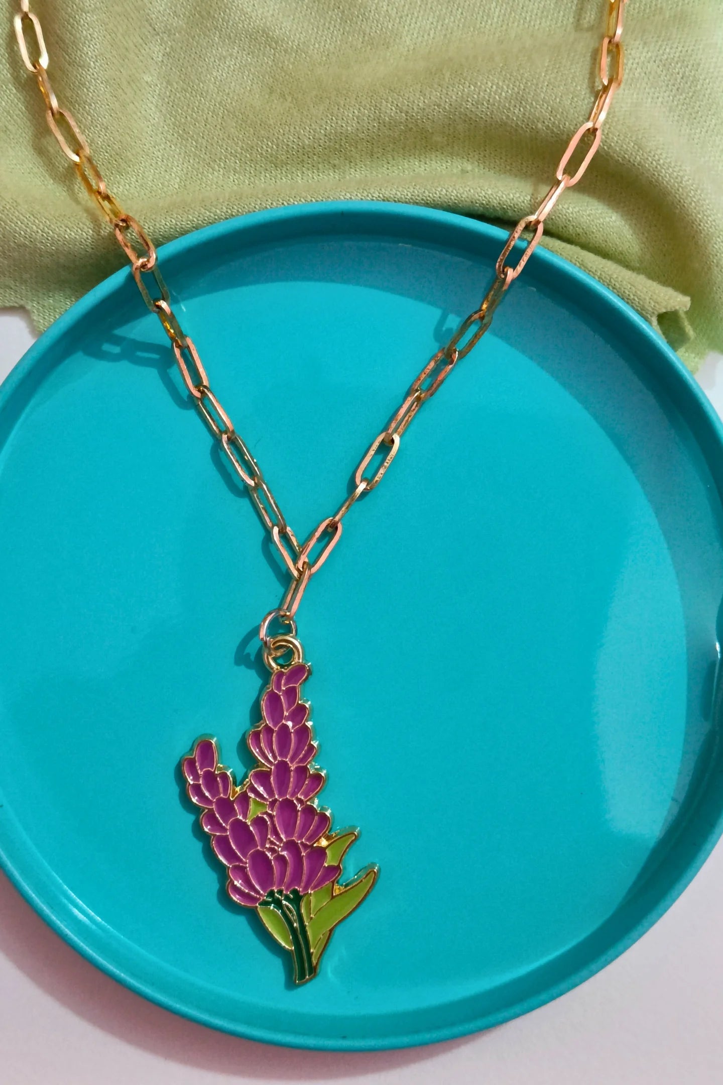 3rd view of a gold chain necklace with a small pendant shaped like a Snapdragon flower.