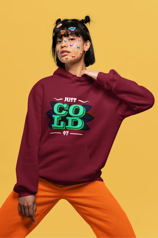 2nd front view of a female model wearing an maroon sweatshirt with the text "Just Cold" printed on it.