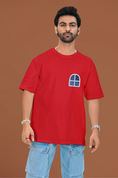 2nd front view of a male model wearing an oversized t-shirt featuring an illustration called Mithi Neend of children lying or sitting on a rooftop, looking up at a starry night sky.