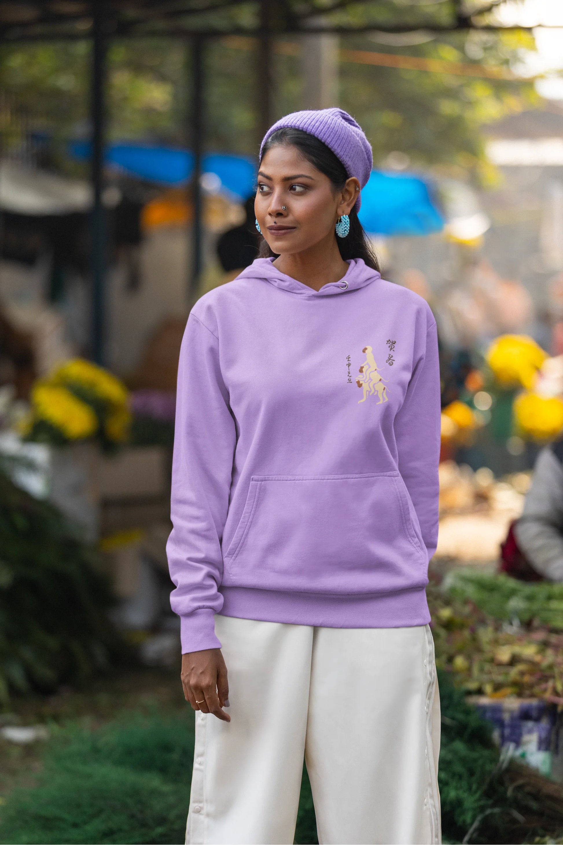 Fifth front view of a female model wearing a lavender hoodie with a design of the three wise monkeys: "See no evil, hear no evil, speak no evil."