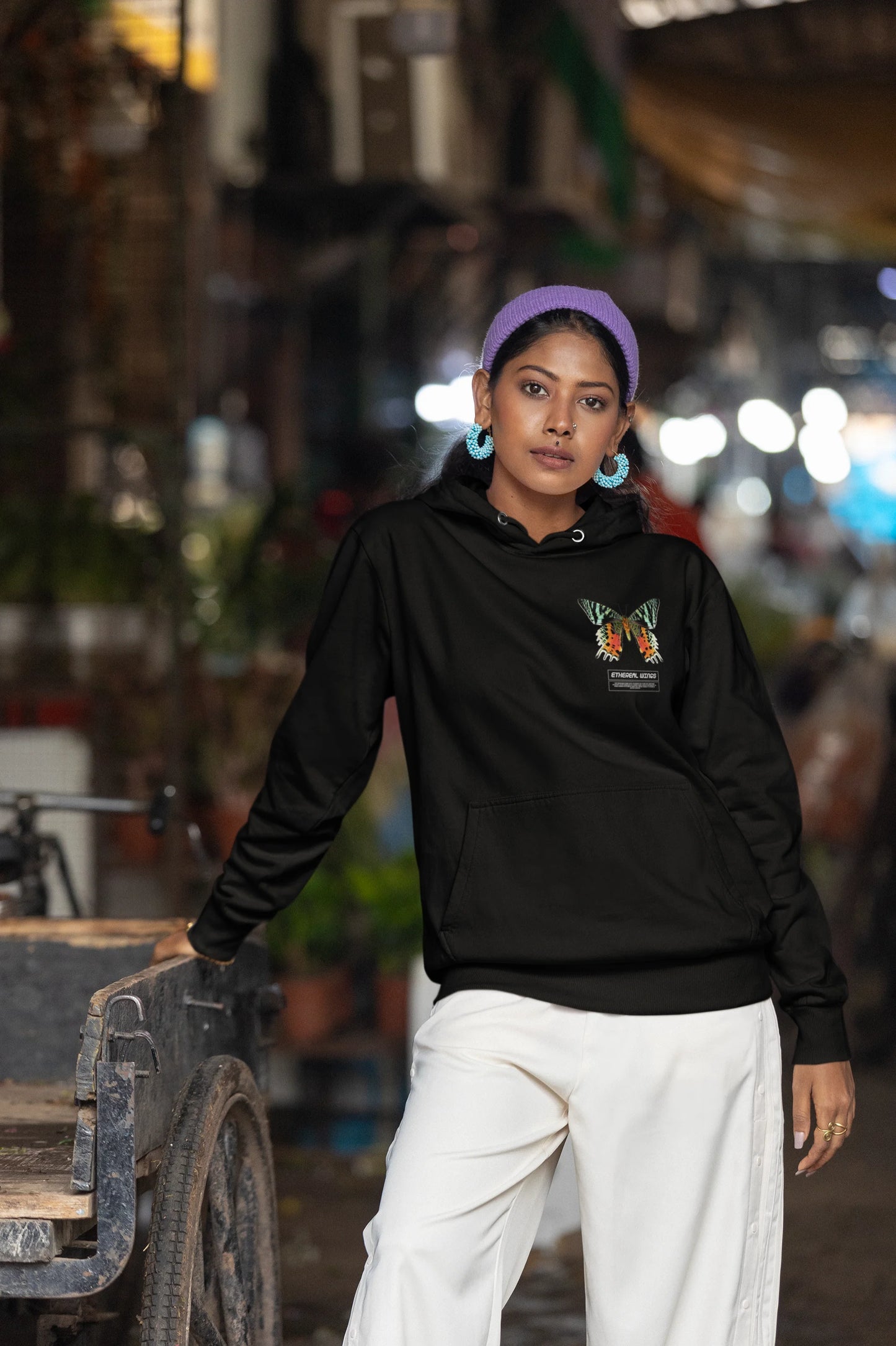 Fourth front view of a female model wearing a black hoodie with a glowing butterfly design, symbolizing the ethereal beauty of nature.