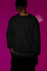 First front view of a male model wearing a black sweatshirt with a heron taking off under the moonlight.