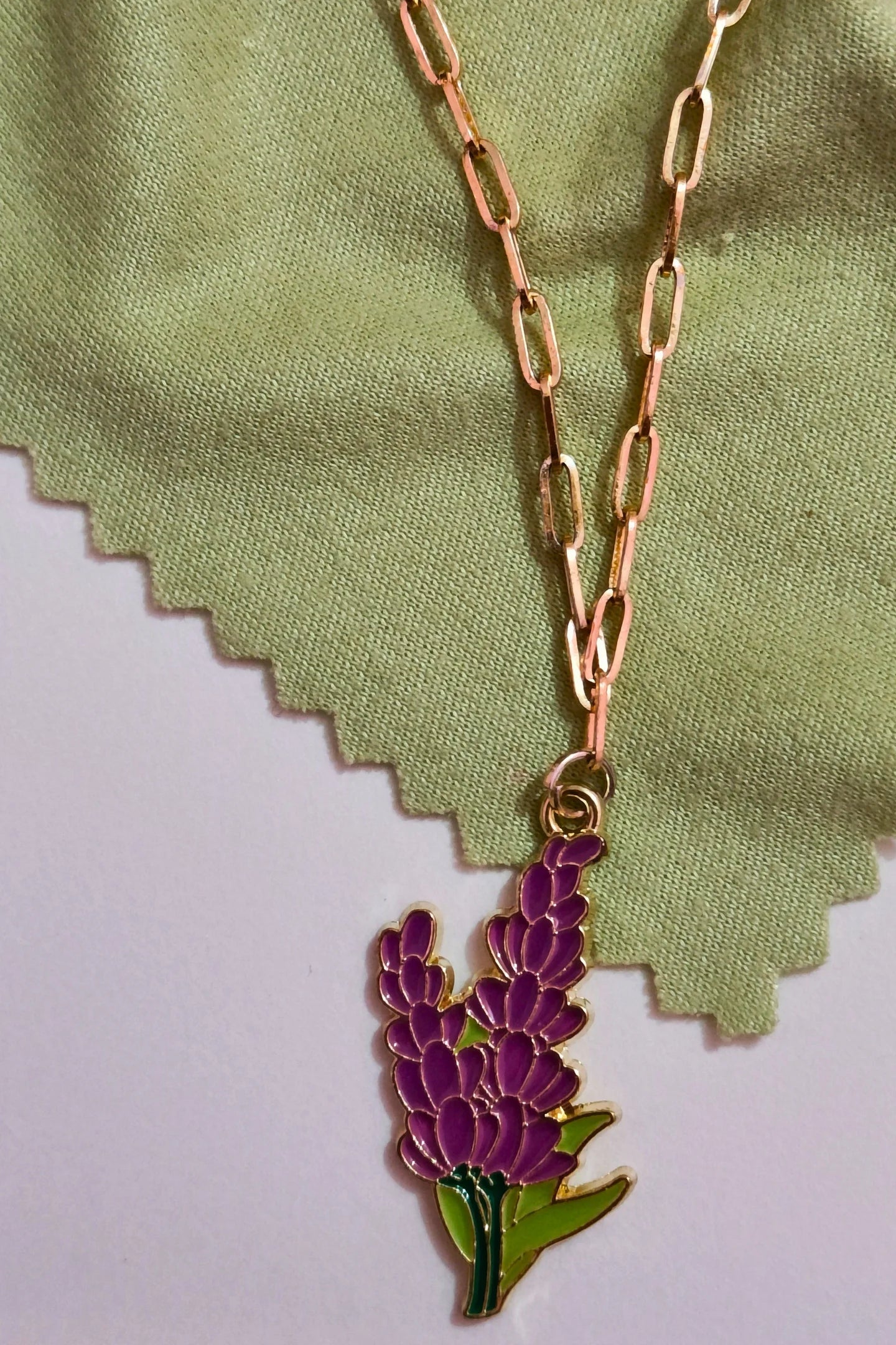 First view of a gold chain necklace with a small pendant shaped like a Snapdragon flower.