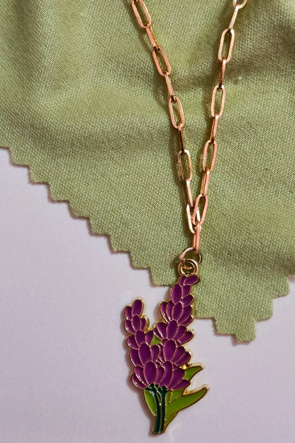 First view of a gold chain necklace with a small pendant shaped like a Snapdragon flower.