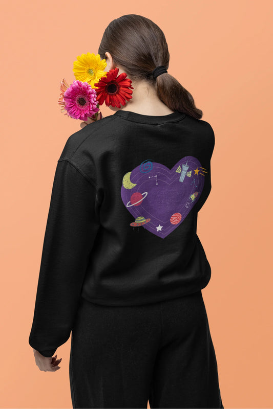 Back view of a female model wearing an black sweatshirt with the "Paradise" album artwork by Coldplay.