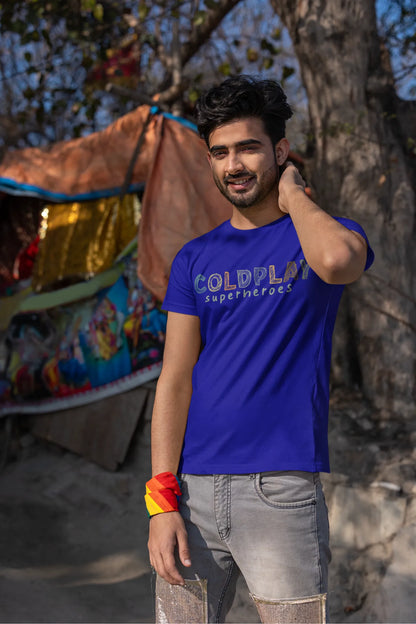 Third view of a male model wearing an royal blue oversized t-shirt with a design inspired by the "Something Just Like This" music video, featuring the word "Superheroes".