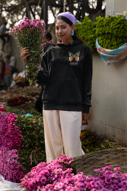 First front view of a female model wearing a black hoodie with a glowing butterfly design, symbolizing the ethereal beauty of nature.