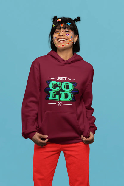 First front view of a female model wearing an maroon sweatshirt with the text "Just Cold" printed on it.