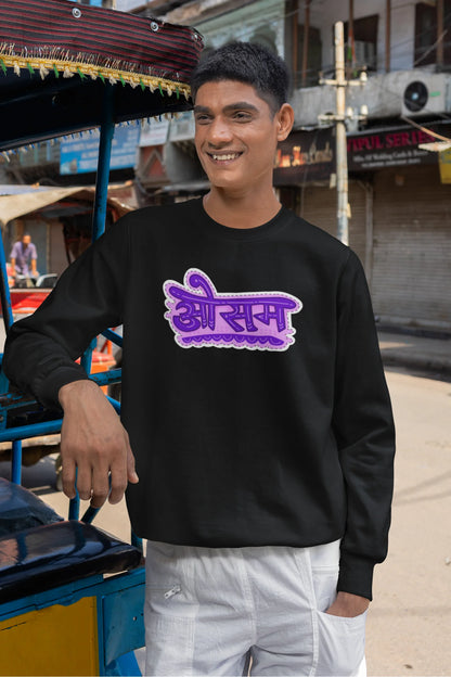 First front view of a male model wearing a black colored oversized graphic t-shirt featuring the word "awesome" in a Hindi script.