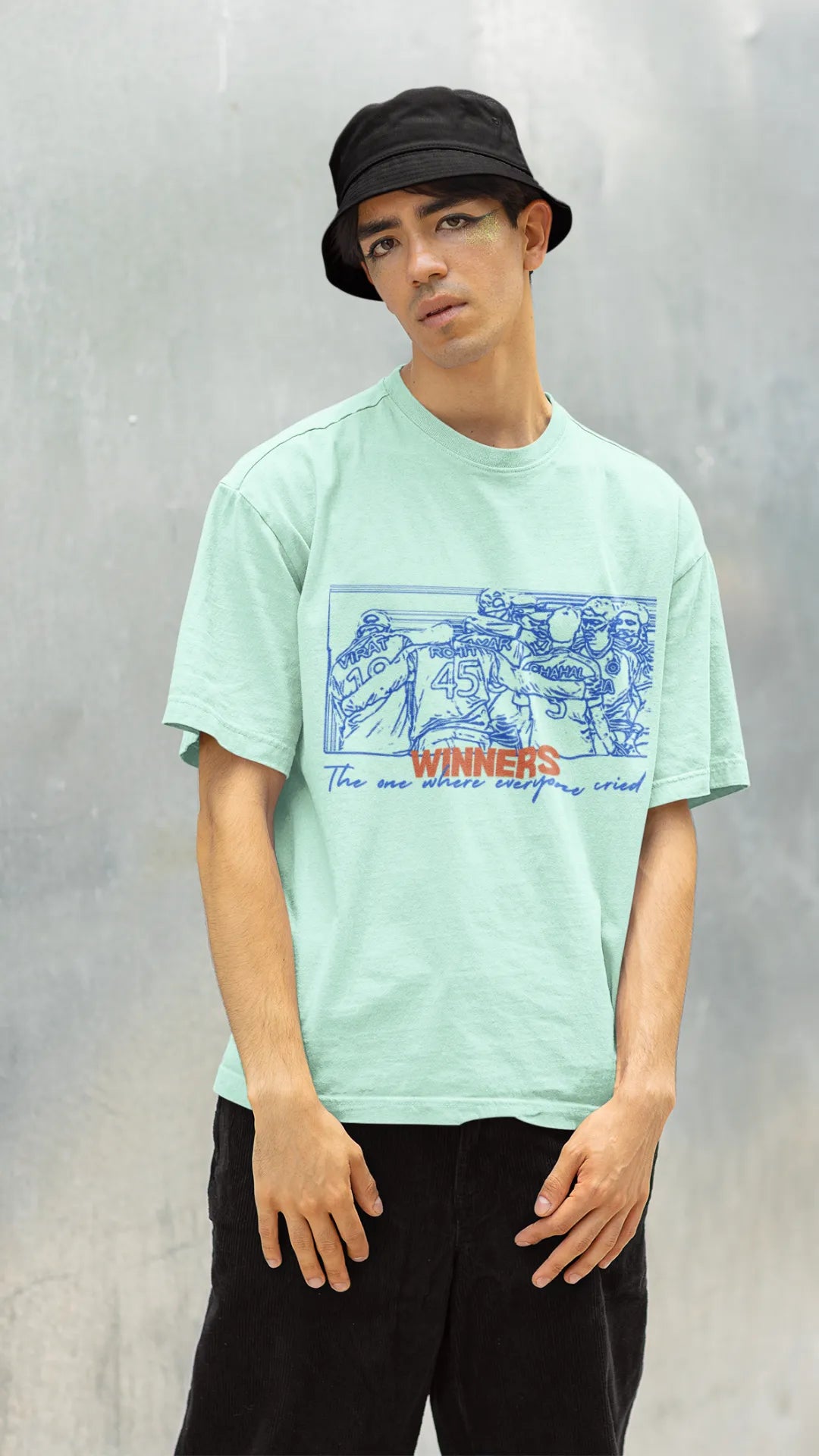 Left side view of a male model wearing an mint-green oversized t-shirt featuring a design of the Indian cricket team in a celebratory huddle with the text "Winners" above them. Ideal for Indian cricket fans commemorating their team's World Cup victory.