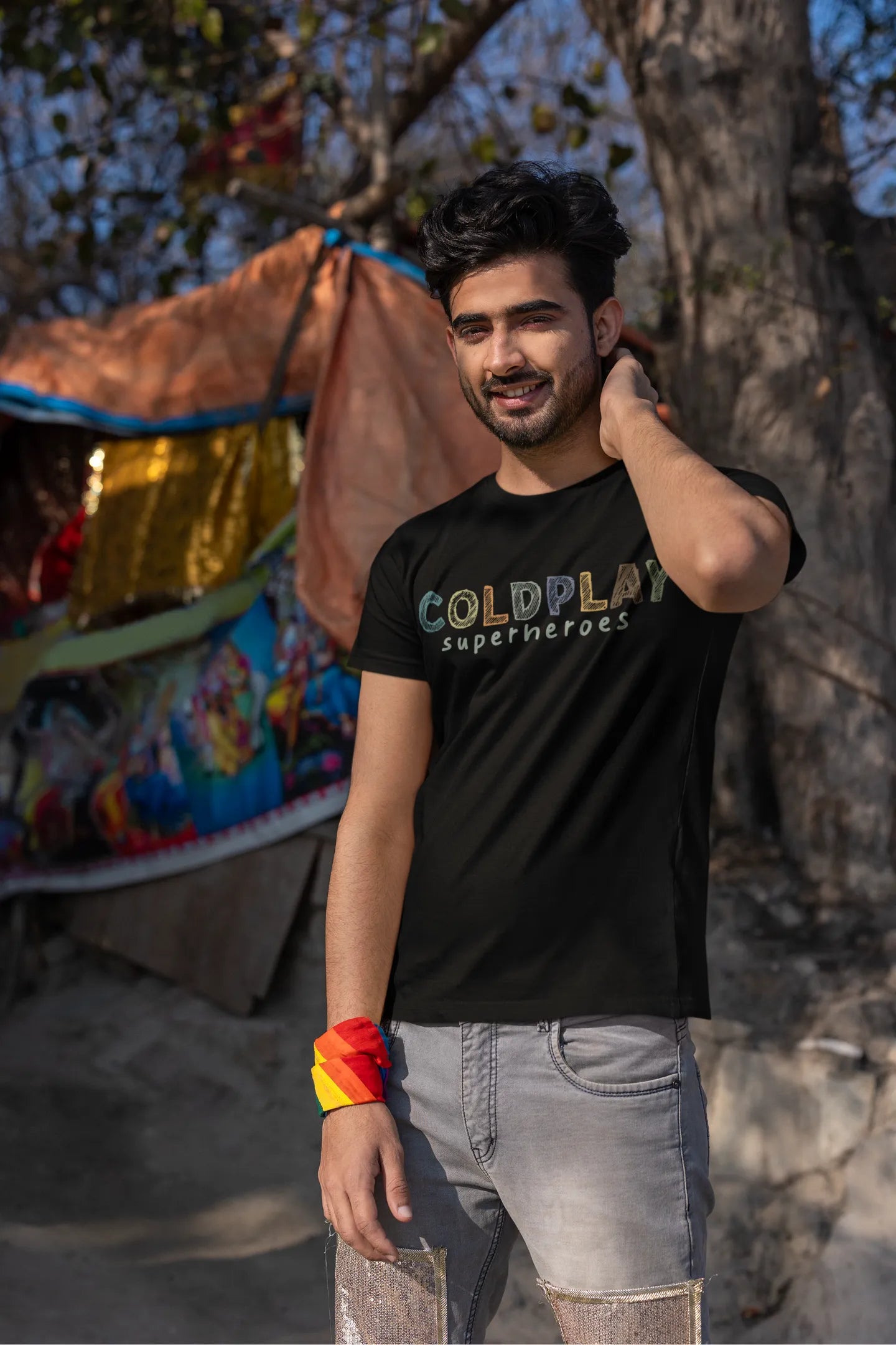 Third view of a male model wearing an black oversized t-shirt with a design inspired by the "Something Just Like This" music video, featuring the word "Superheroes".
