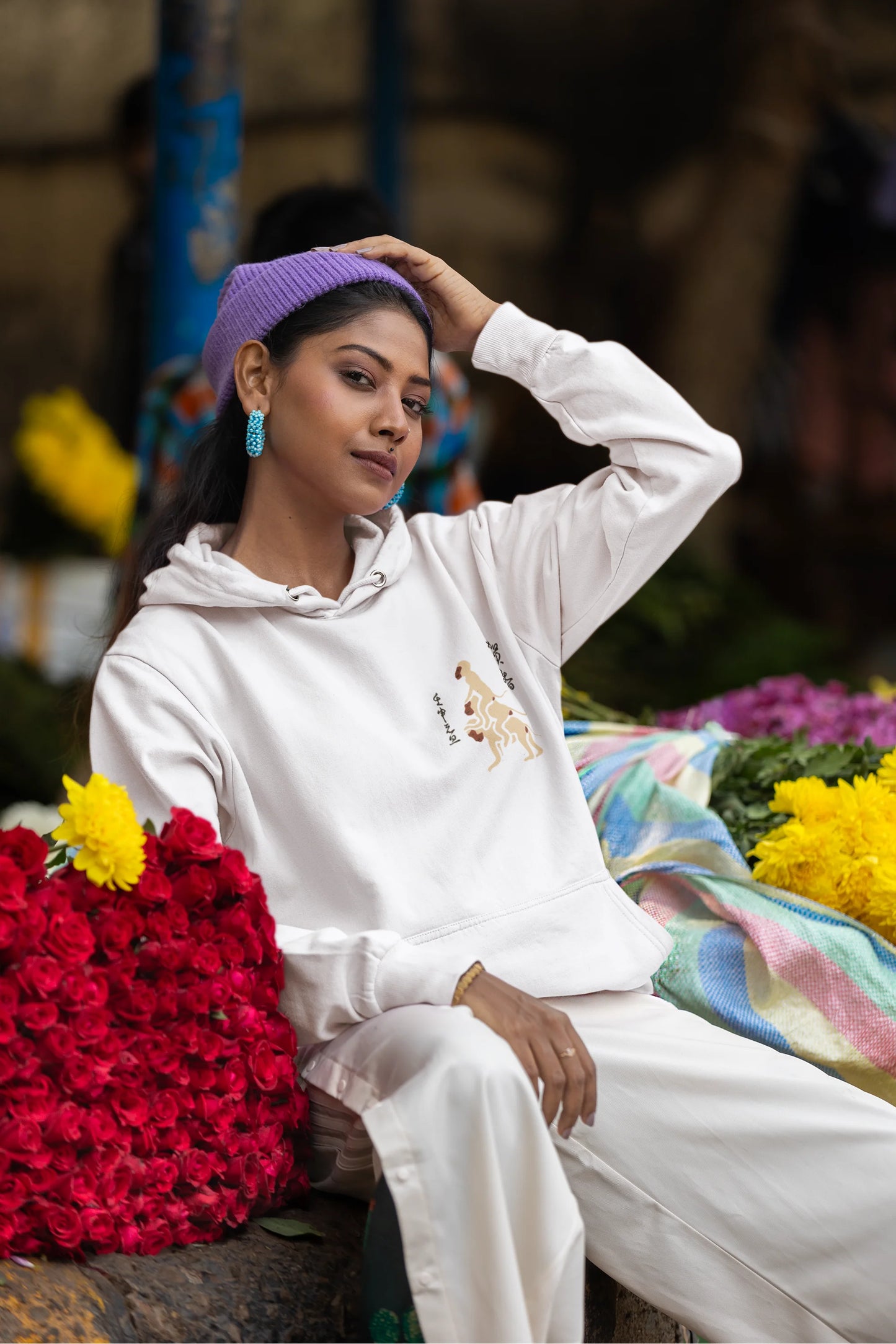 Fourth front view of a female model wearing a white hoodie with a design of the three wise monkeys: "See no evil, hear no evil, speak no evil."
