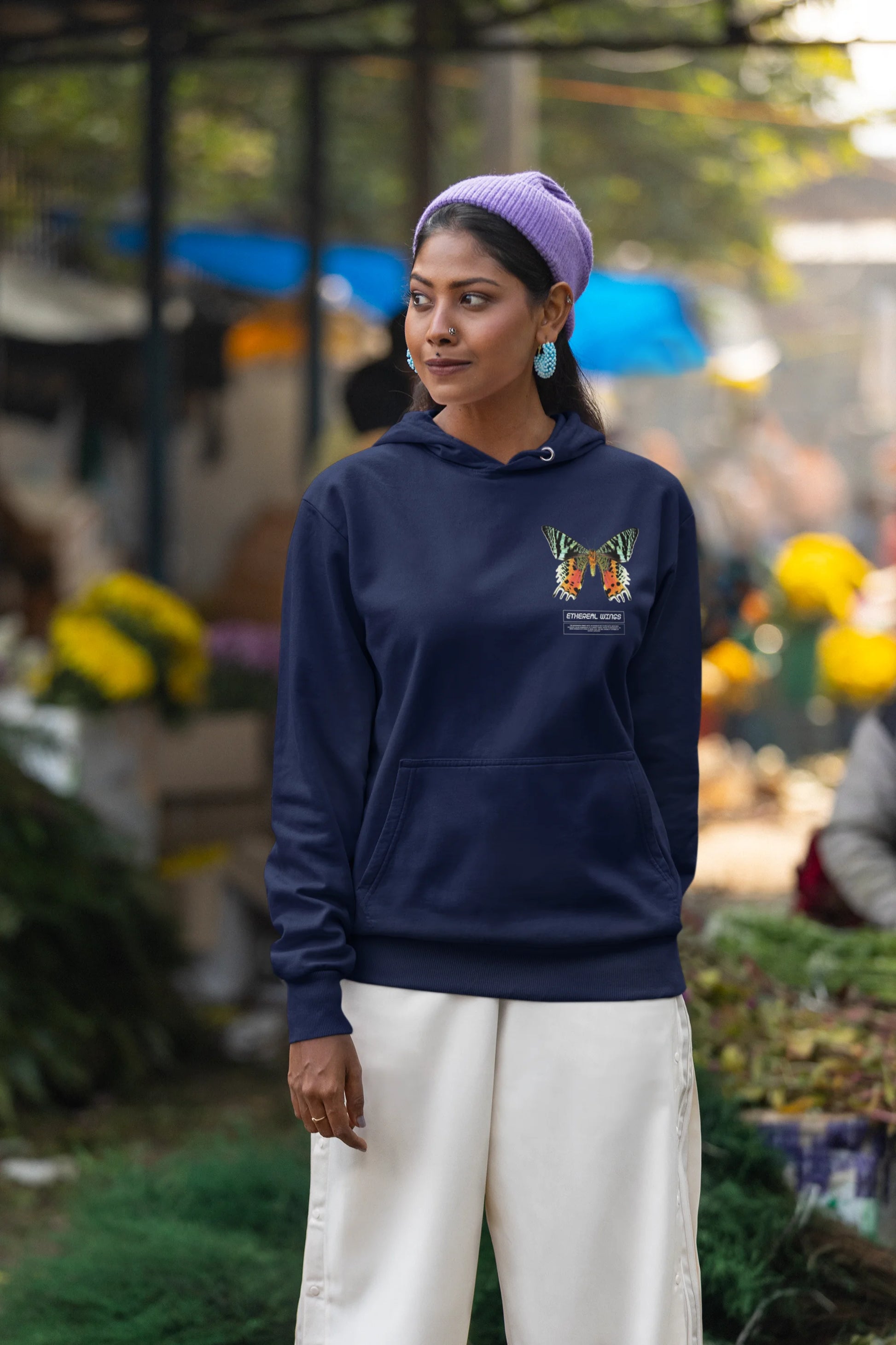 First front view of a female model wearing a navy blue hoodie with a glowing butterfly design, symbolizing the ethereal beauty of nature.