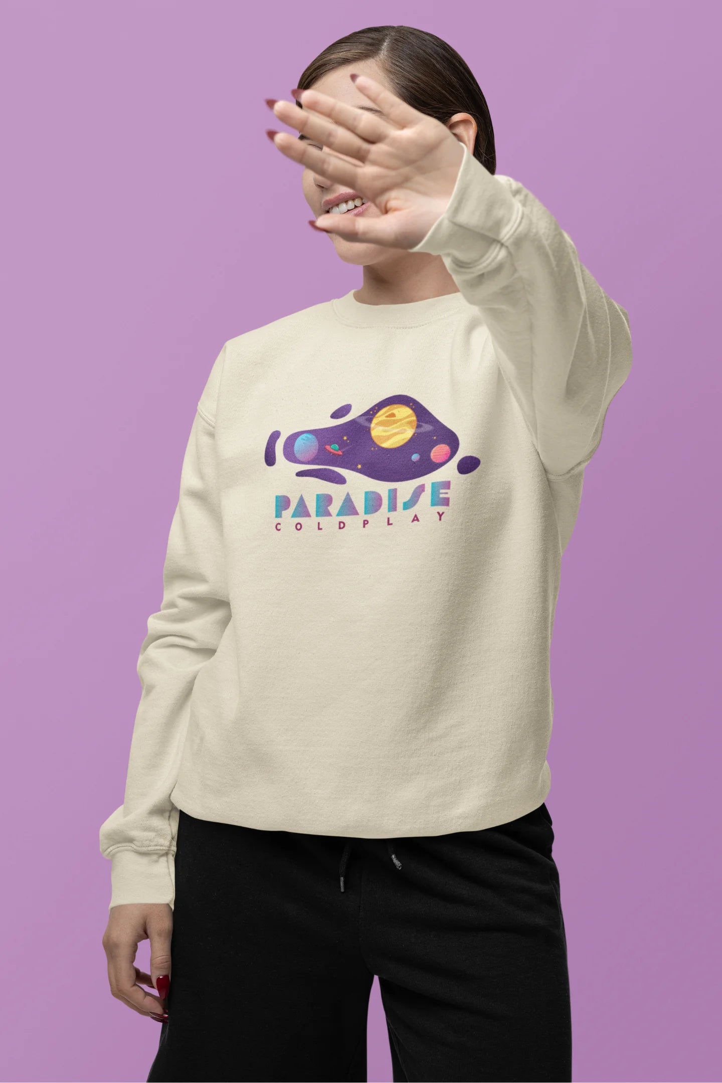 Second front view of a female model wearing an cream sweatshirt with the "Paradise" album artwork by Coldplay.