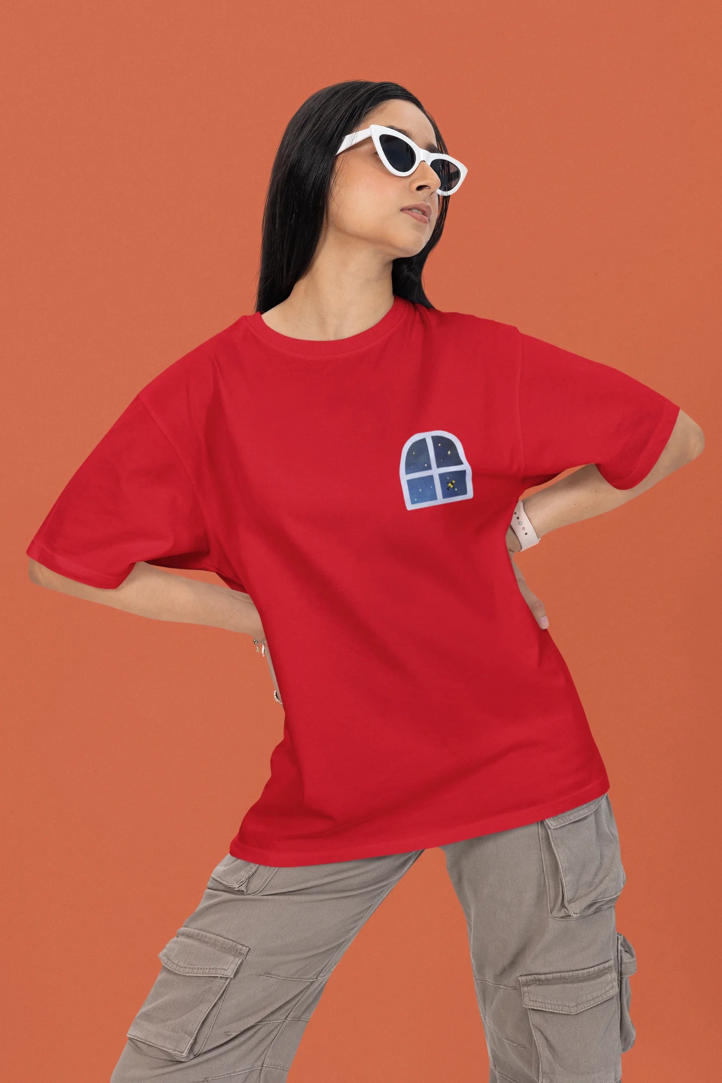 2nd front view of a female model wearing an oversized t-shirt featuring an illustration called Mithi Neend of children lying or sitting on a rooftop, looking up at a starry night sky.
