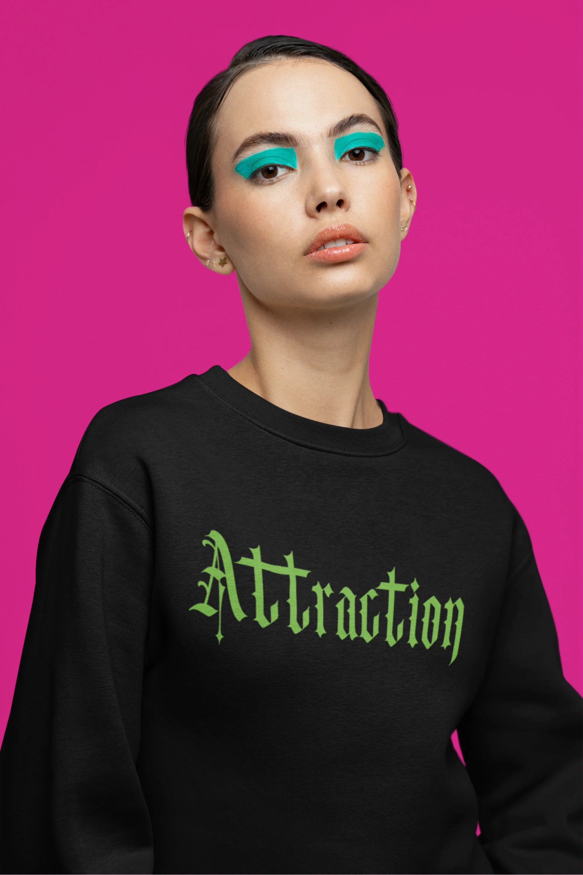 Fifth front view of a female model wearing a black sweatshirt with a brutalist design featuring two statues kissing and the word "Attraction".