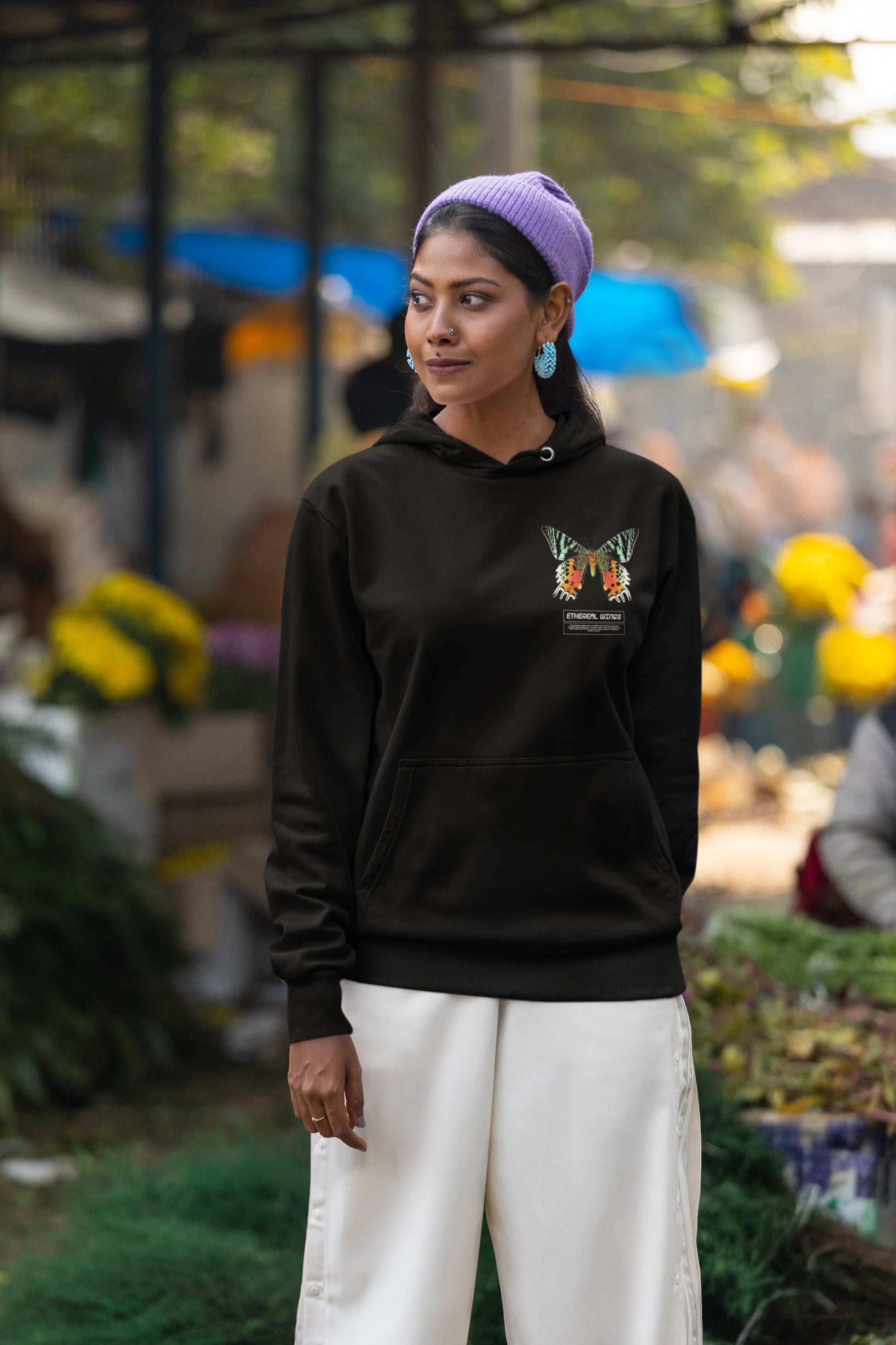 Third front view of a female model wearing a black hoodie with a glowing butterfly design, symbolizing the ethereal beauty of nature.