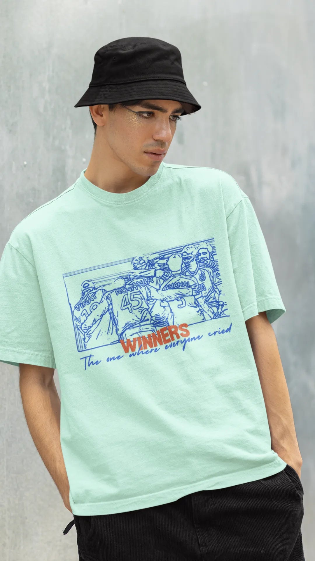 Right side view of a male model wearing an mint-green oversized t-shirt featuring a design of the Indian cricket team in a celebratory huddle with the text "Winners" above them. Ideal for Indian cricket fans commemorating their team's World Cup victory.