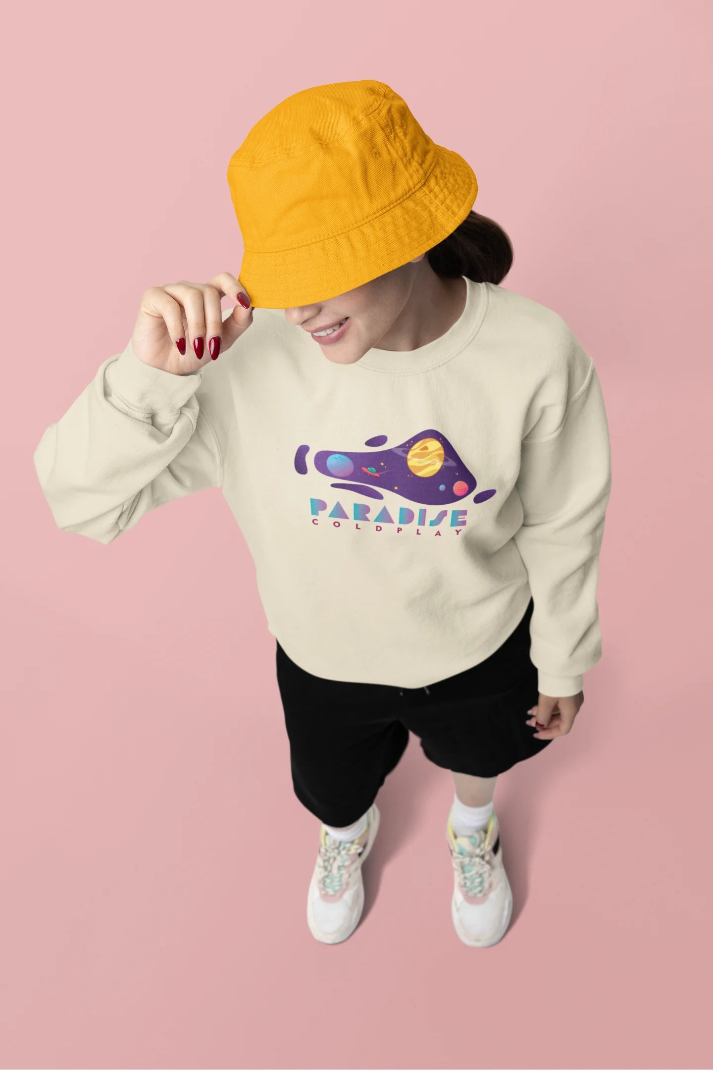 Fourth view of a female model wearing an cream sweatshirt with the "Paradise" album artwork by Coldplay.