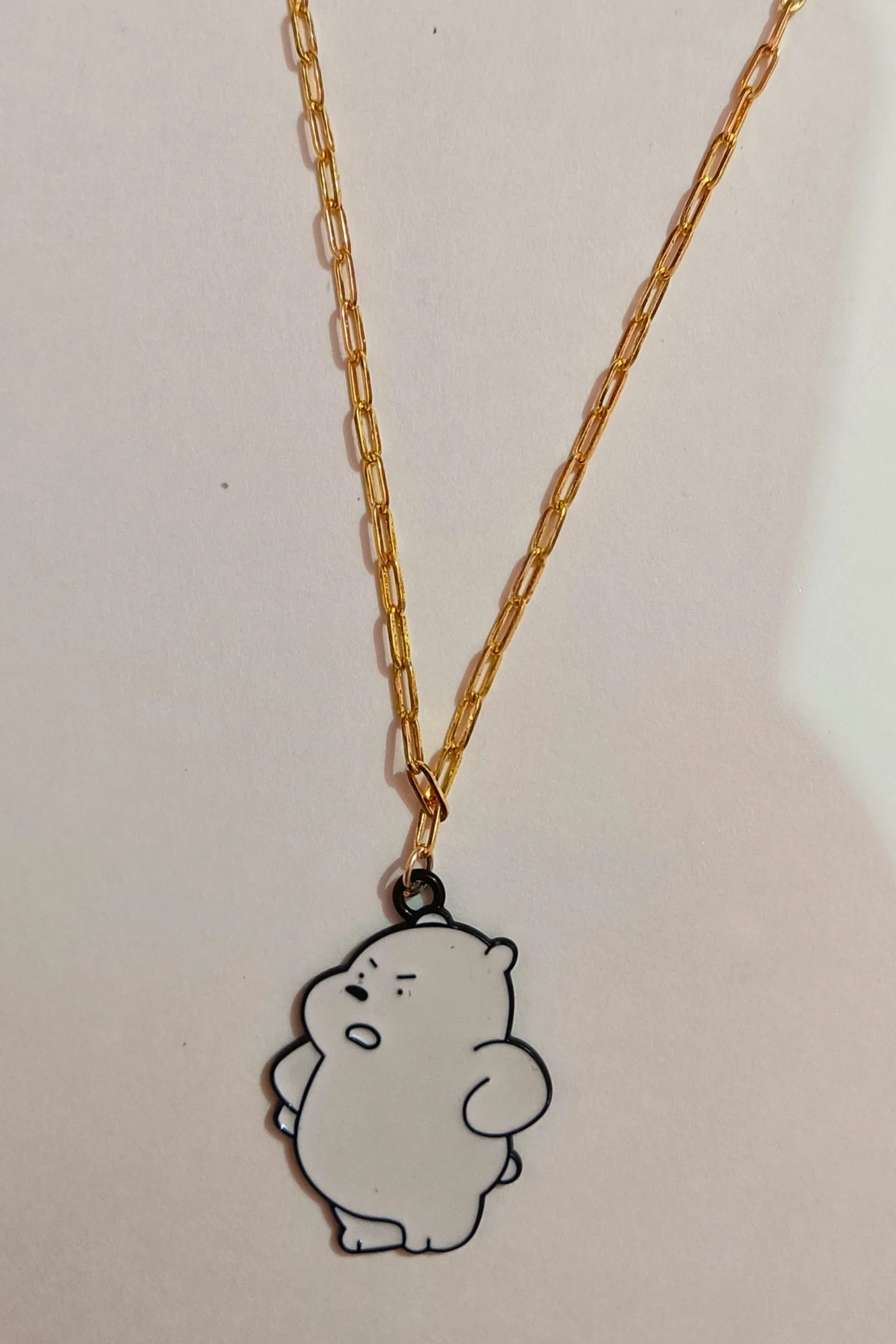 3rd view of a gold chain necklace with a small pendant shaped like Ice Bear