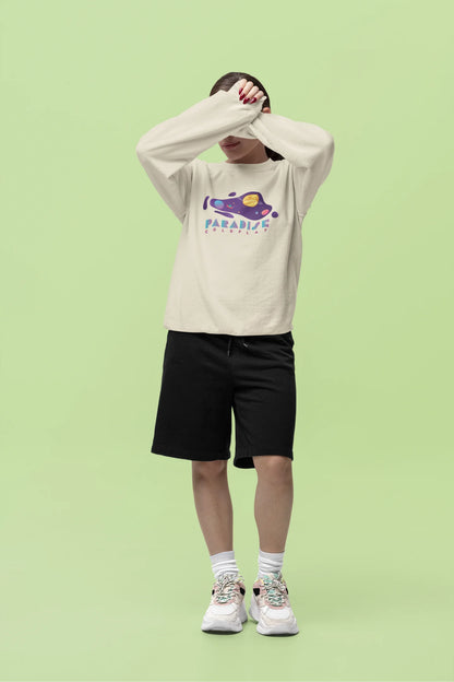 Fifth front view of a female model wearing an cream sweatshirt with the "Paradise" album artwork by Coldplay.