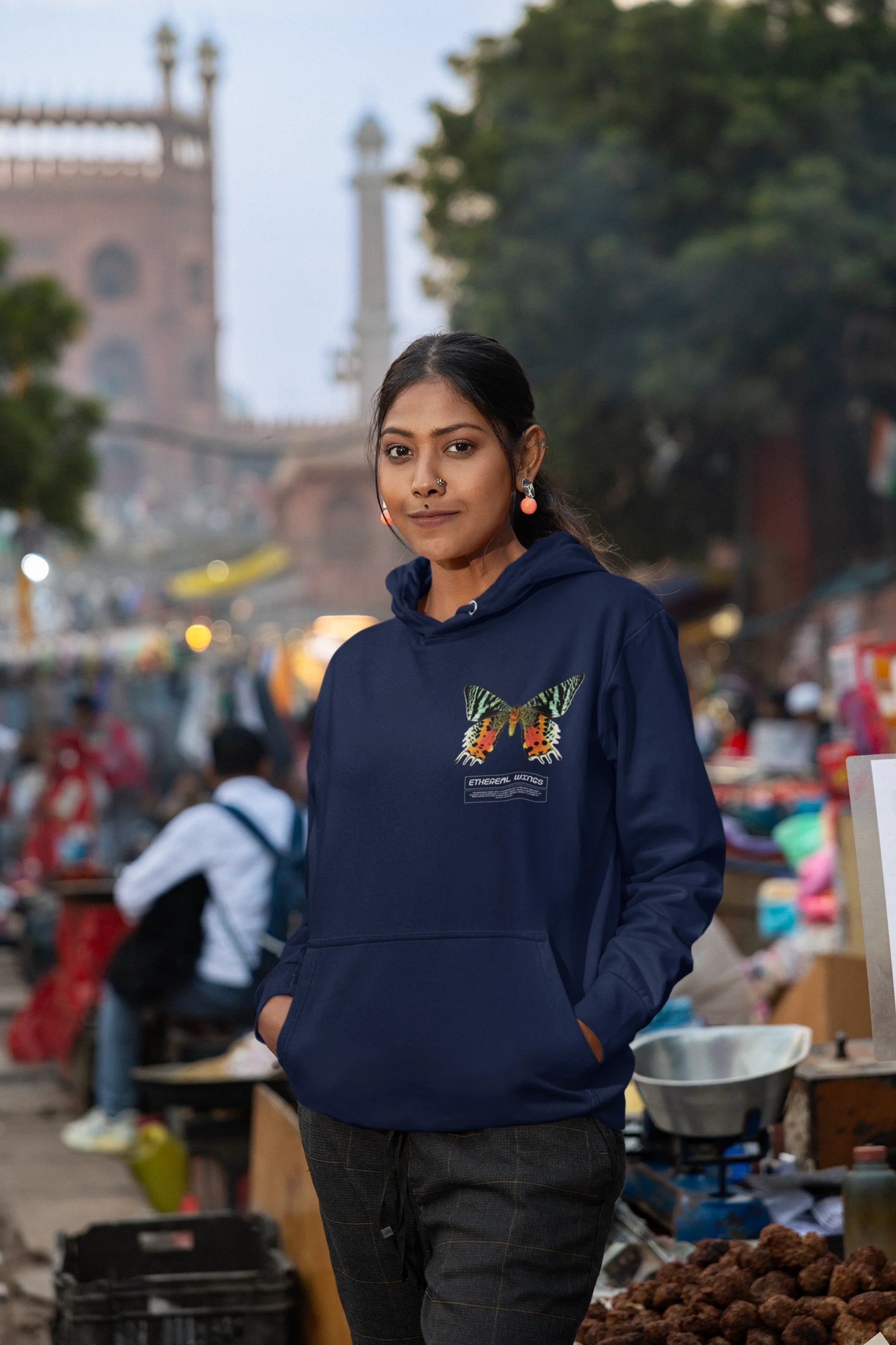 Sixth front view of a female model wearing a navy blue hoodie with a glowing butterfly design, symbolizing the ethereal beauty of nature.