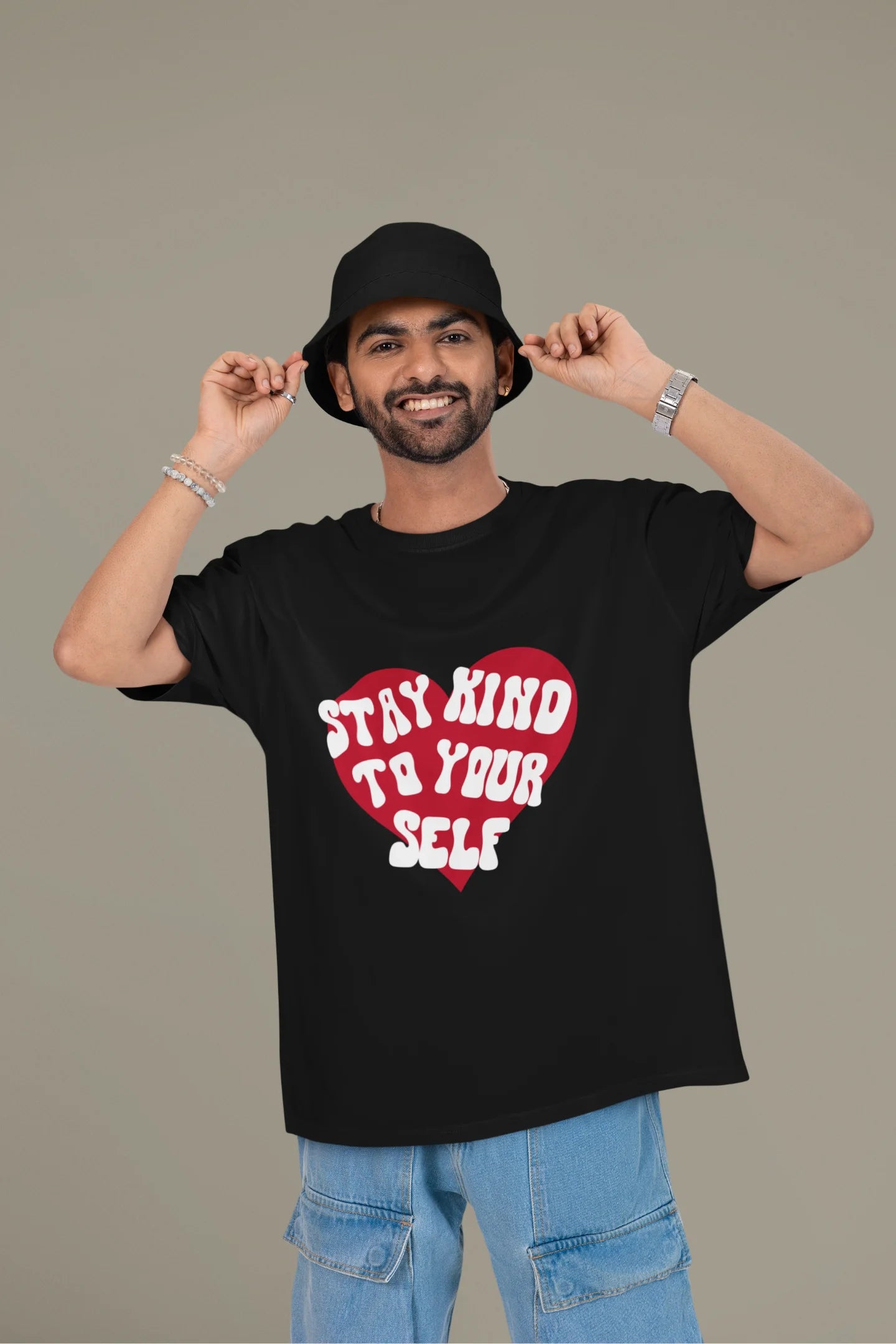 First front view of a male model wearing a black oversized t-shirt with the text "Stay Kind" printed on it.