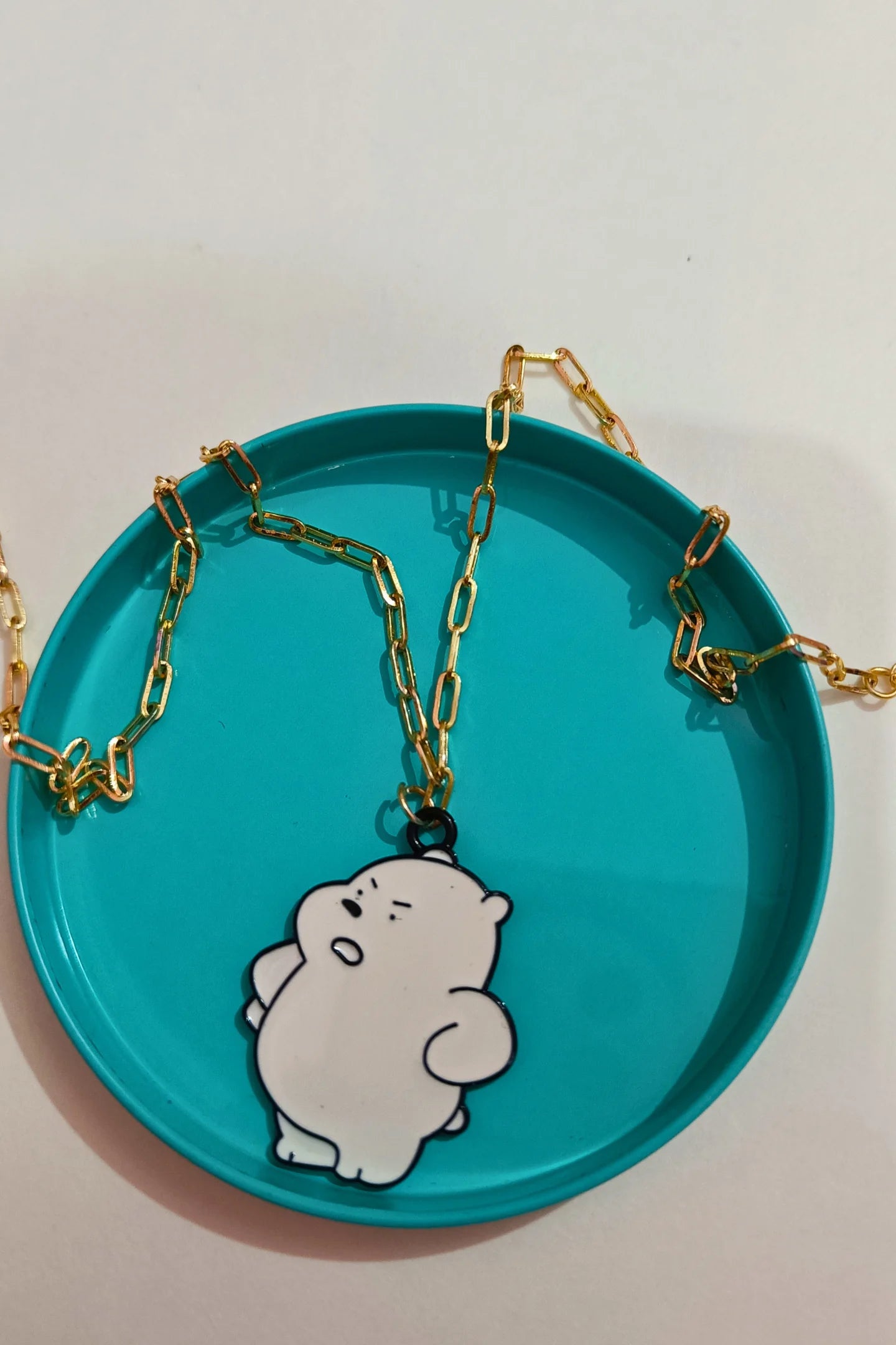 2nd view of a gold chain necklace with a small pendant shaped like Ice Bear