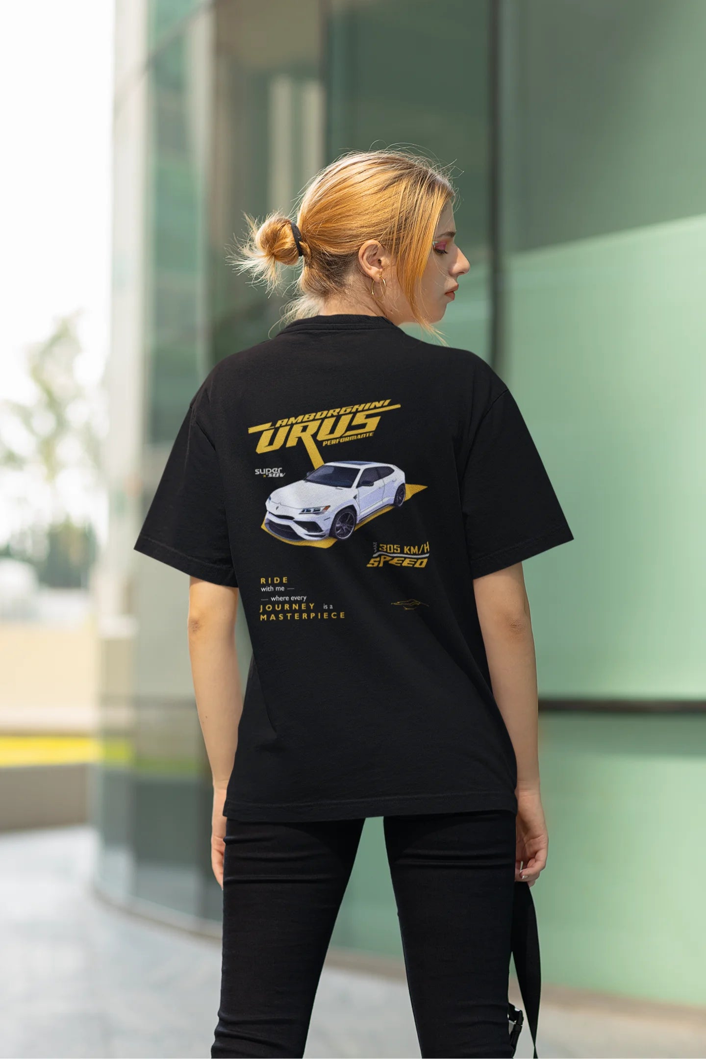 Back view of a female model wearing a black oversized t-shirt featuring a design of a Lamborghini Urus.