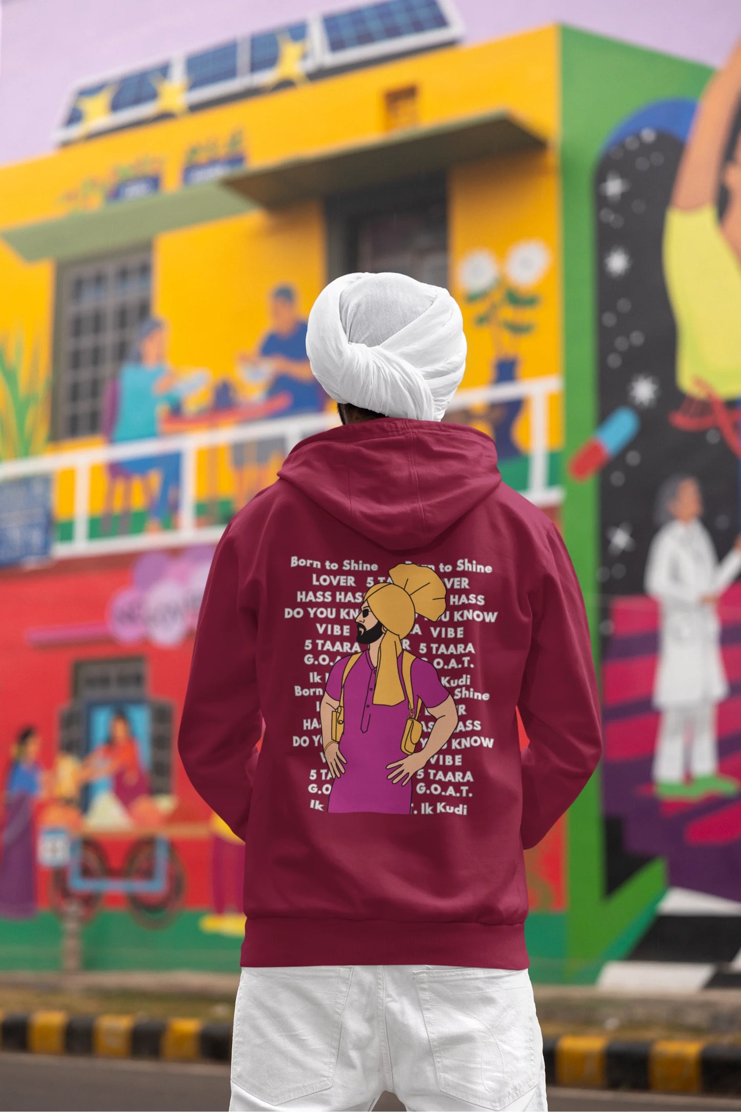Back view of a male model wearing a maroon hoodie with a portrait of Diljit Dosanjh and lyrics from the song "Ikk Kudi."