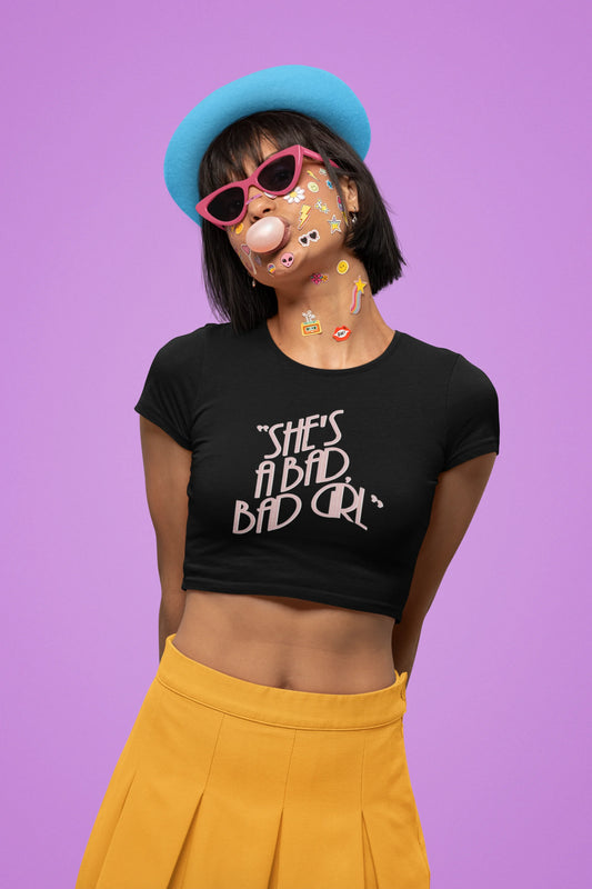 First front view of a female model wearing a black crop top with "She's a bad bad girl" text, perfect for Swifties and Eras Tour fans.