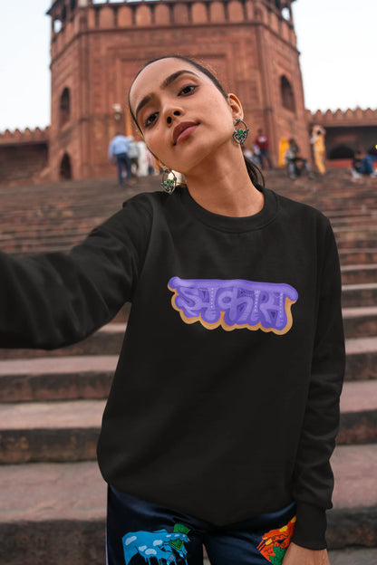 4th front view of a female model wearing an black sweatshirt featuring "Jhakas" in a stylish font.