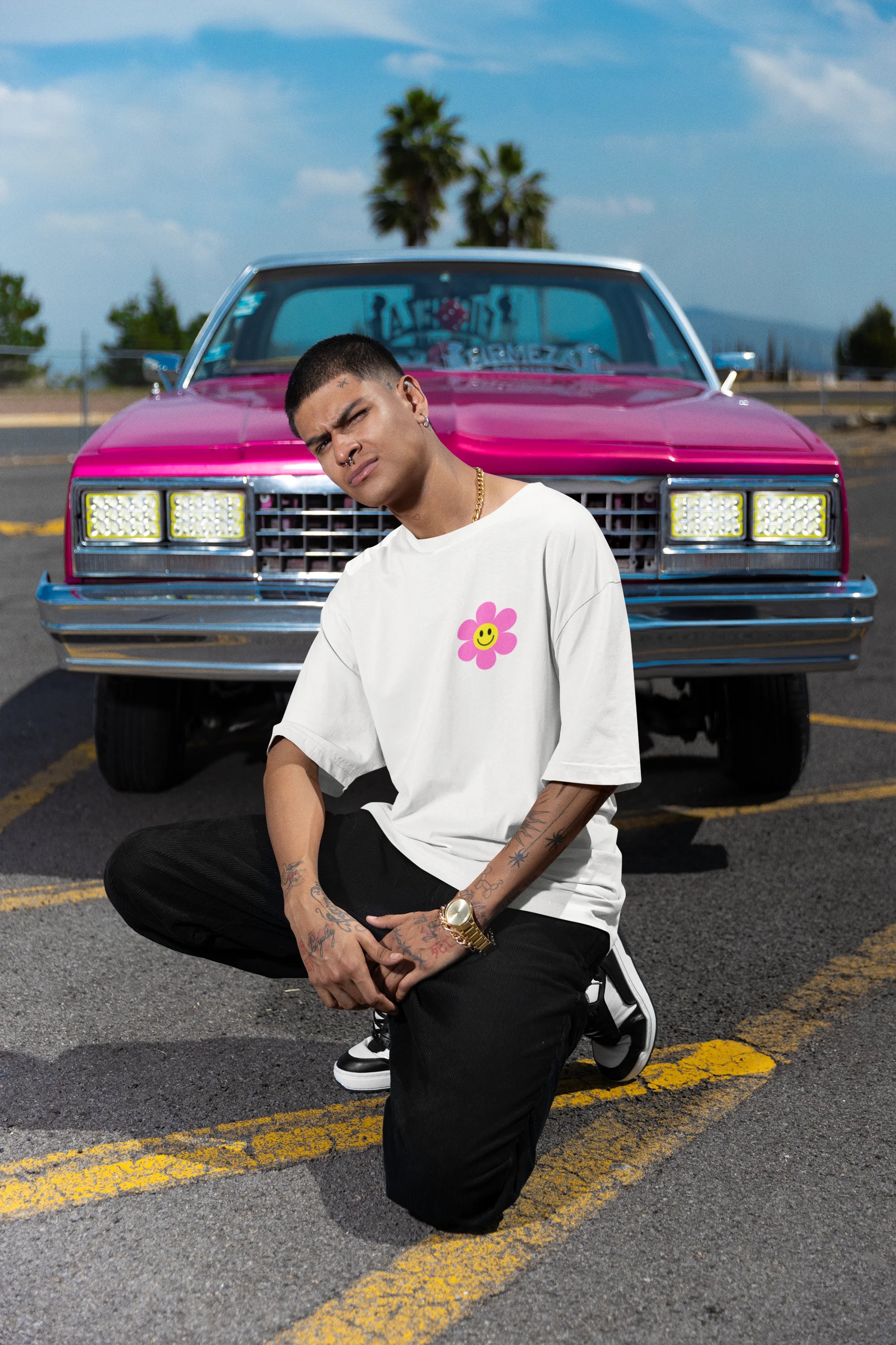 Right side view of a male model wearing an oversized off-white t-shirt with a positive message "Keep Smiling" surrounded by colorful flowers and a smiley face emoji. Ideal for those who love cheerful clothing and spreading positivity.