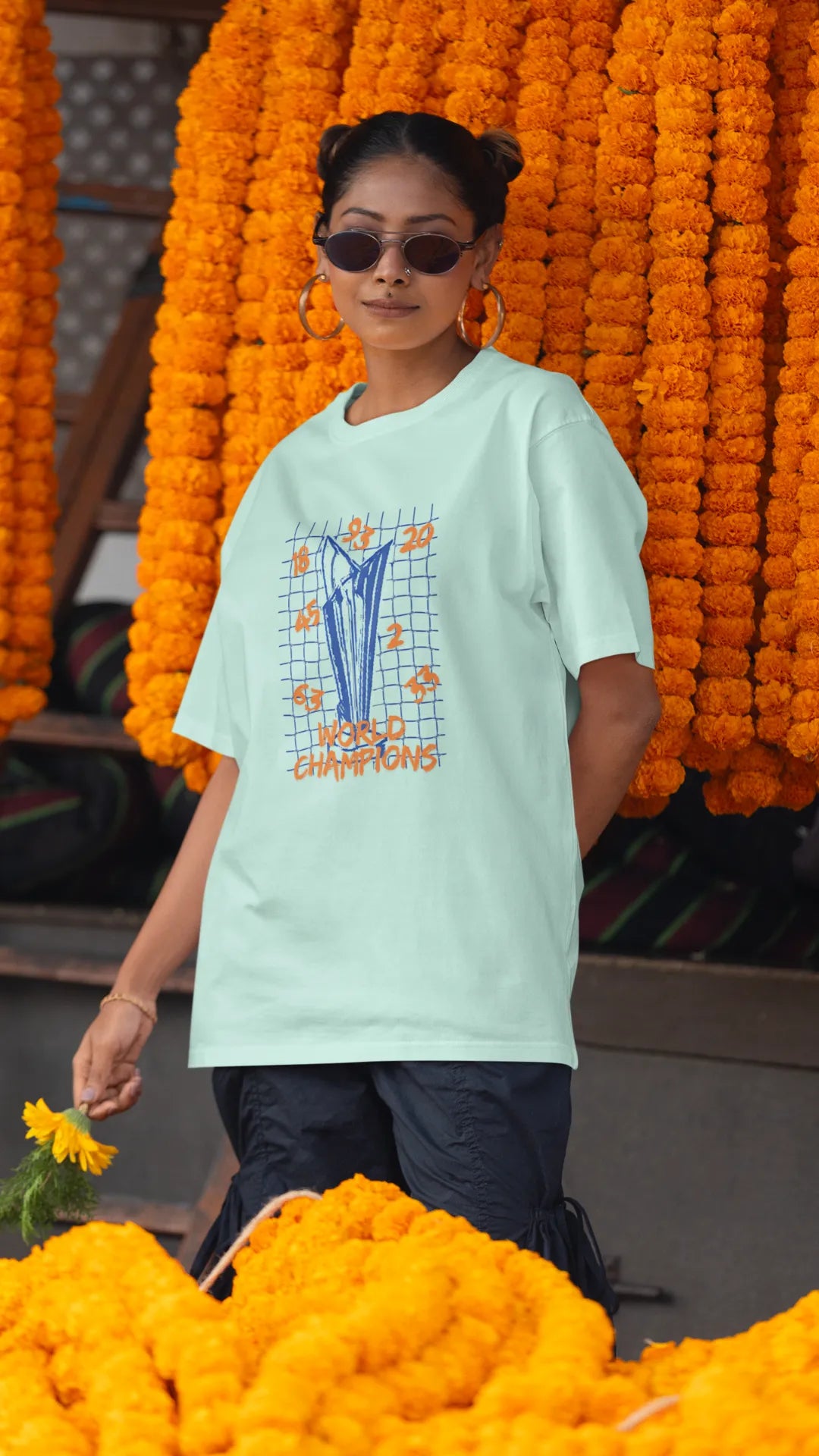 Second front image of female model wearing a mint green oversized t-shirt featuring the World Cup 2024 trophy with the text "World Champions" underneath. Ideal for Indian cricket fans celebrating their team's victory.