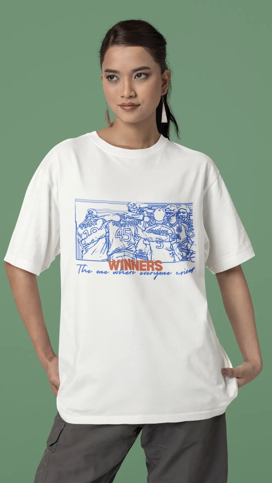 Front view of a female model wearing an of-white oversized t-shirt featuring a design of the Indian cricket team in a celebratory huddle with the text "Winners" above them. Ideal for Indian cricket fans commemorating their team's World Cup victory.