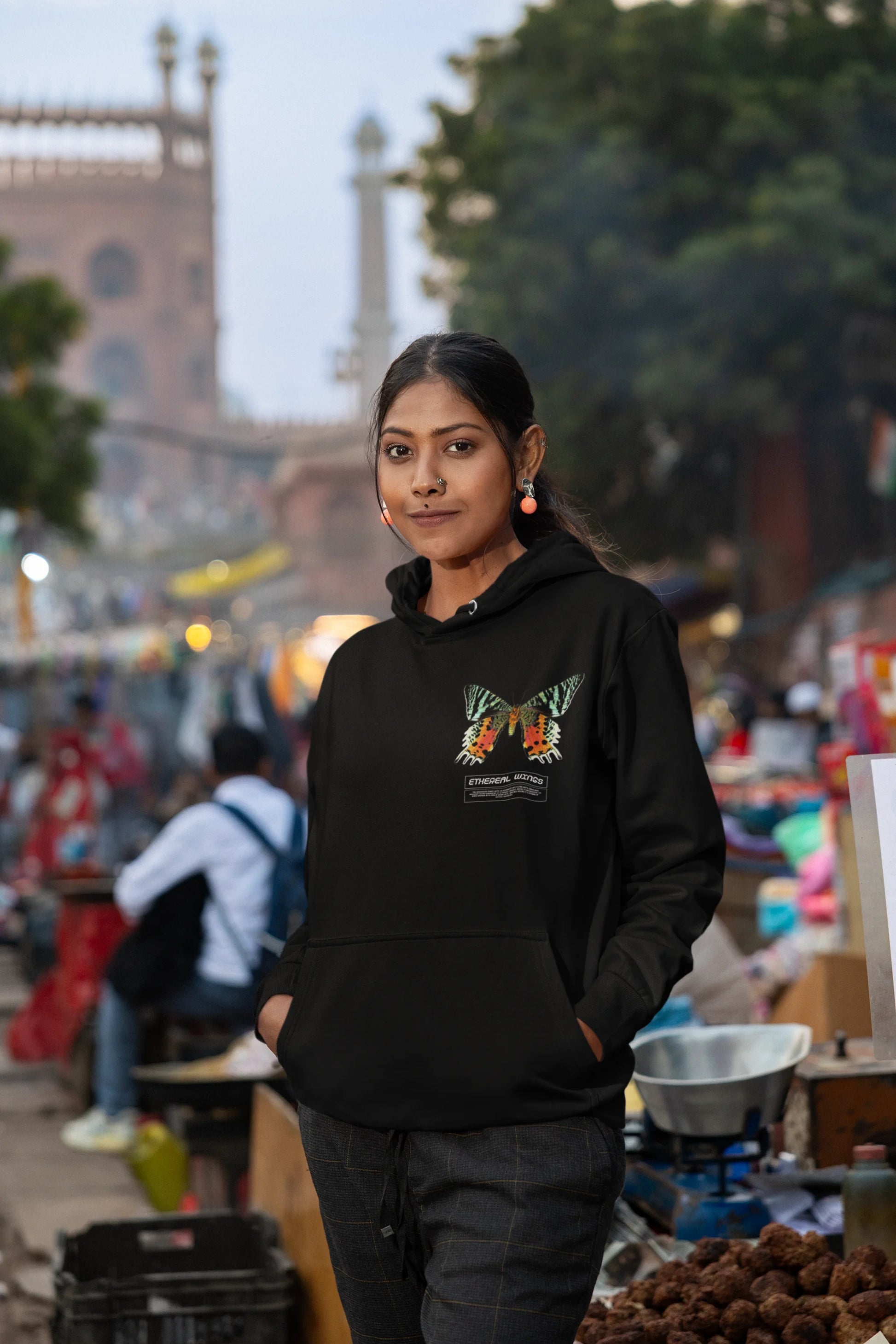 Sixth front view of a female model wearing a black hoodie with a glowing butterfly design, symbolizing the ethereal beauty of nature.