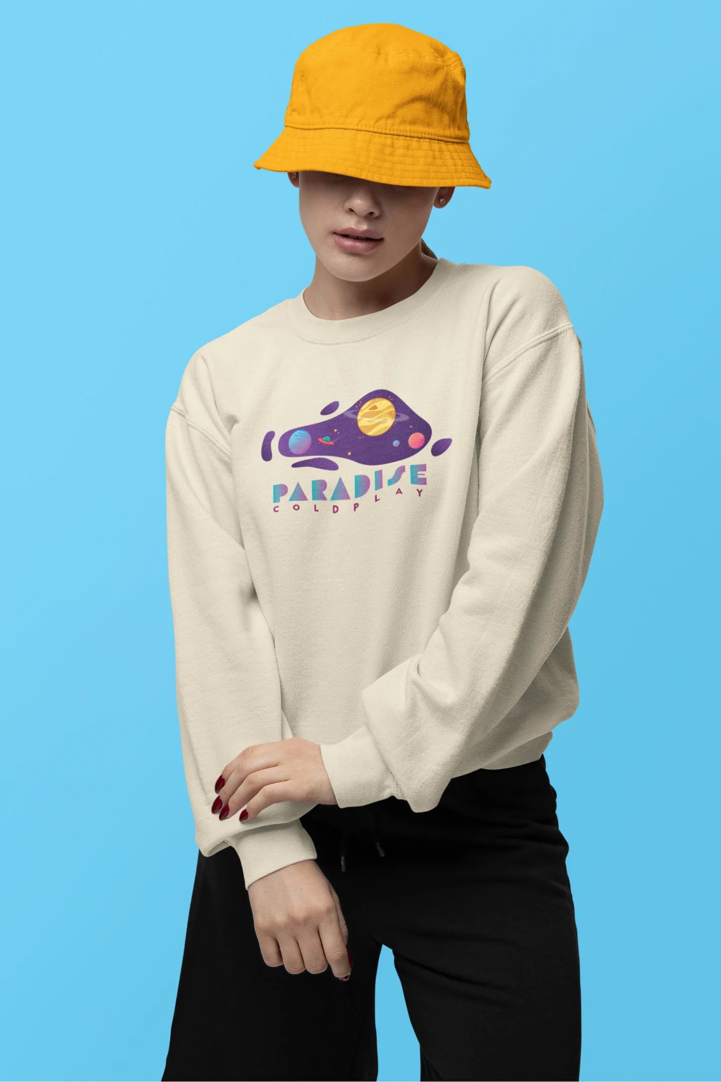 First front view of a female model wearing an cream sweatshirt with the "Paradise" album artwork by Coldplay.