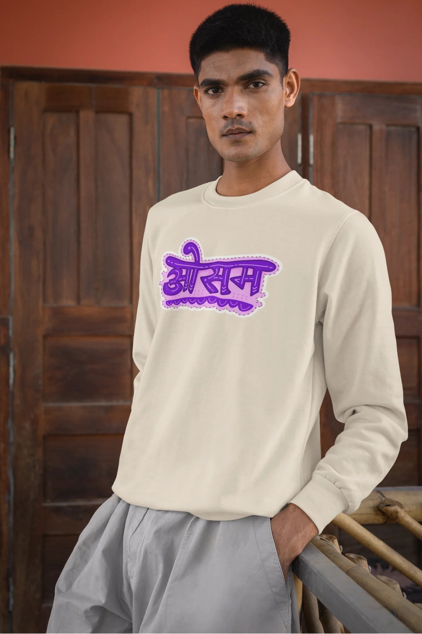 3rd front view of a male model wearing a cream colored oversized graphic t-shirt featuring the word "awesome" in a Hindi script.