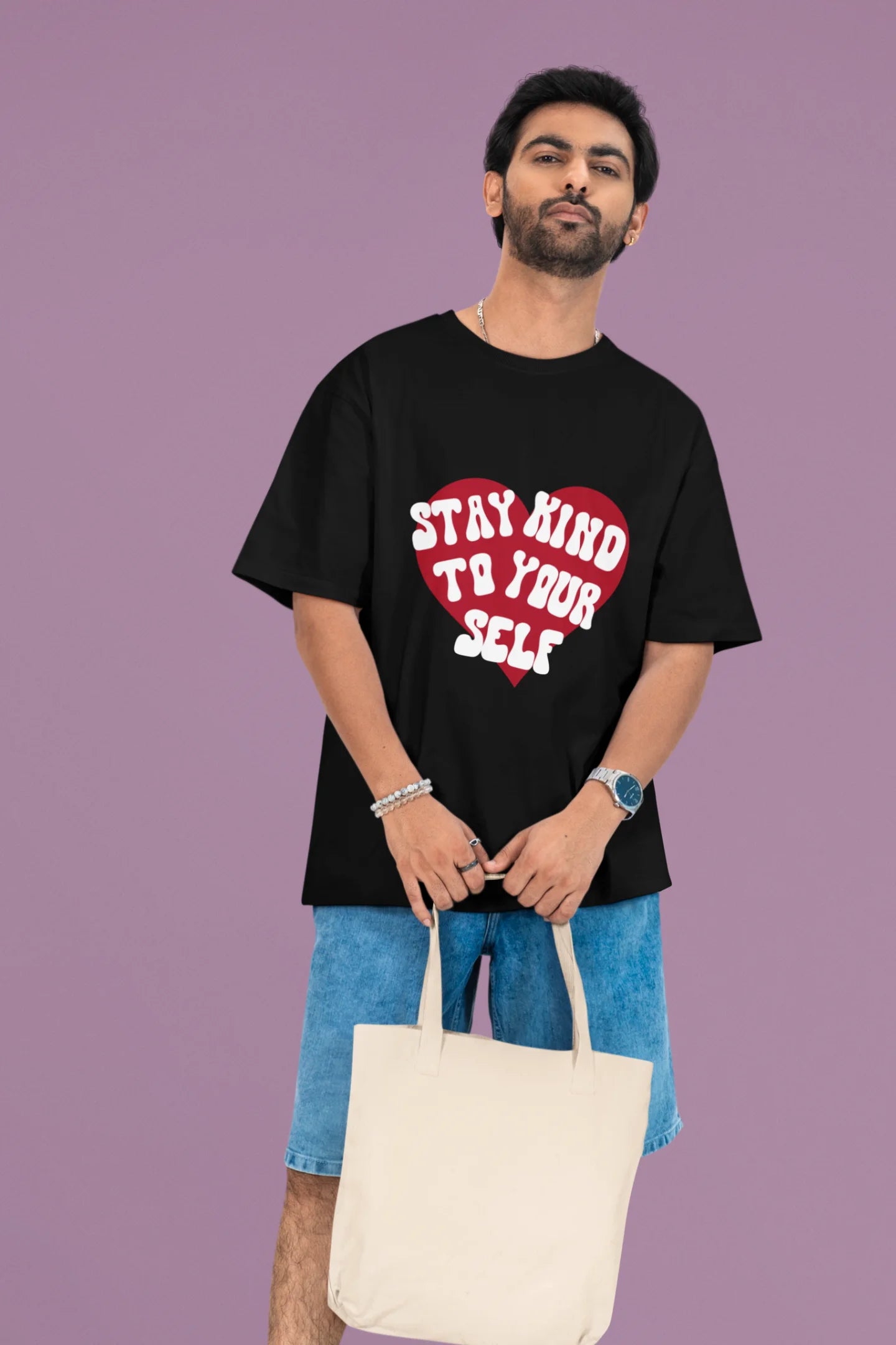 2nd front view of a male model wearing a black oversized t-shirt with the text "Stay Kind" printed on it.