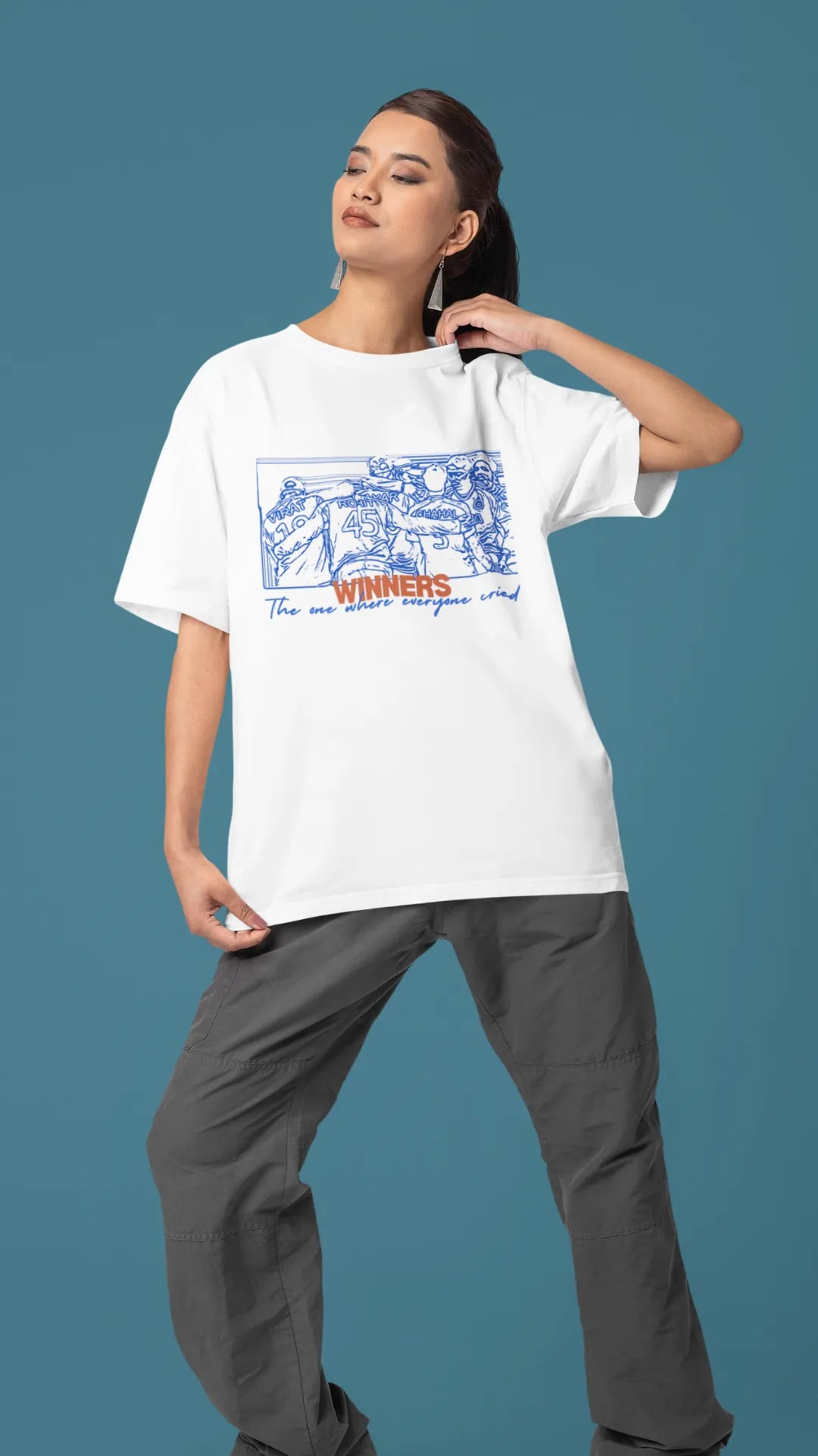 Right side view of a female model wearing an of-white oversized t-shirt featuring a design of the Indian cricket team in a celebratory huddle with the text "Winners" above them. Ideal for Indian cricket fans commemorating their team's World Cup victory.